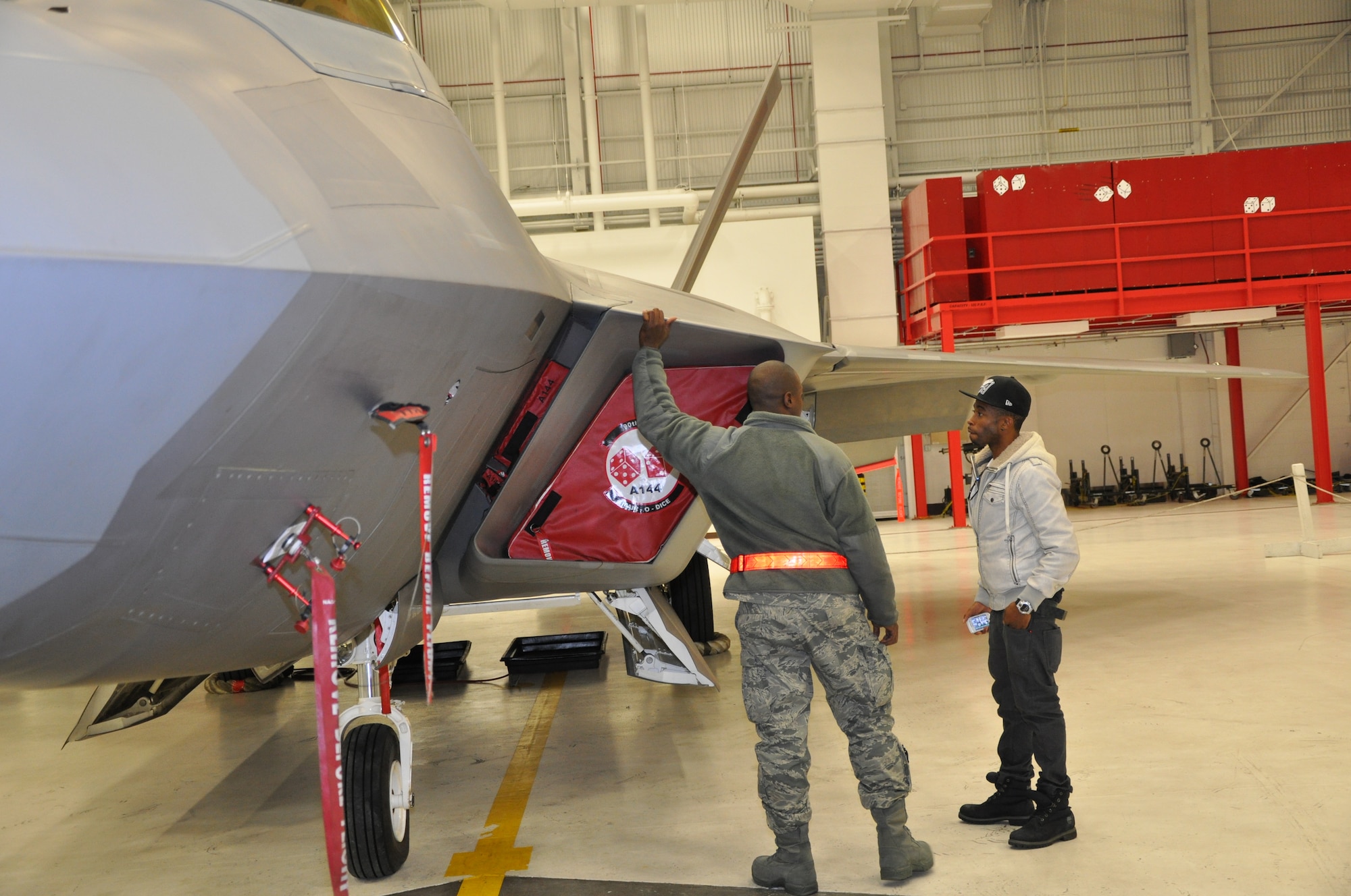 Senior Airman Marren Clay, 477th Aircraft Maintenance Squadron crew chief, gives a tour of the F-22 to actor Marcus Paulk. Paulk plays Deke Watkins in the new George Lucas film, Red Tails, about the Tuskegee Airmen. An advanced screening was held for a small group of Reservists and Anchorage citizens Dec 15. (U. S. Air Force Photo/Capt. Ashley Conner)
