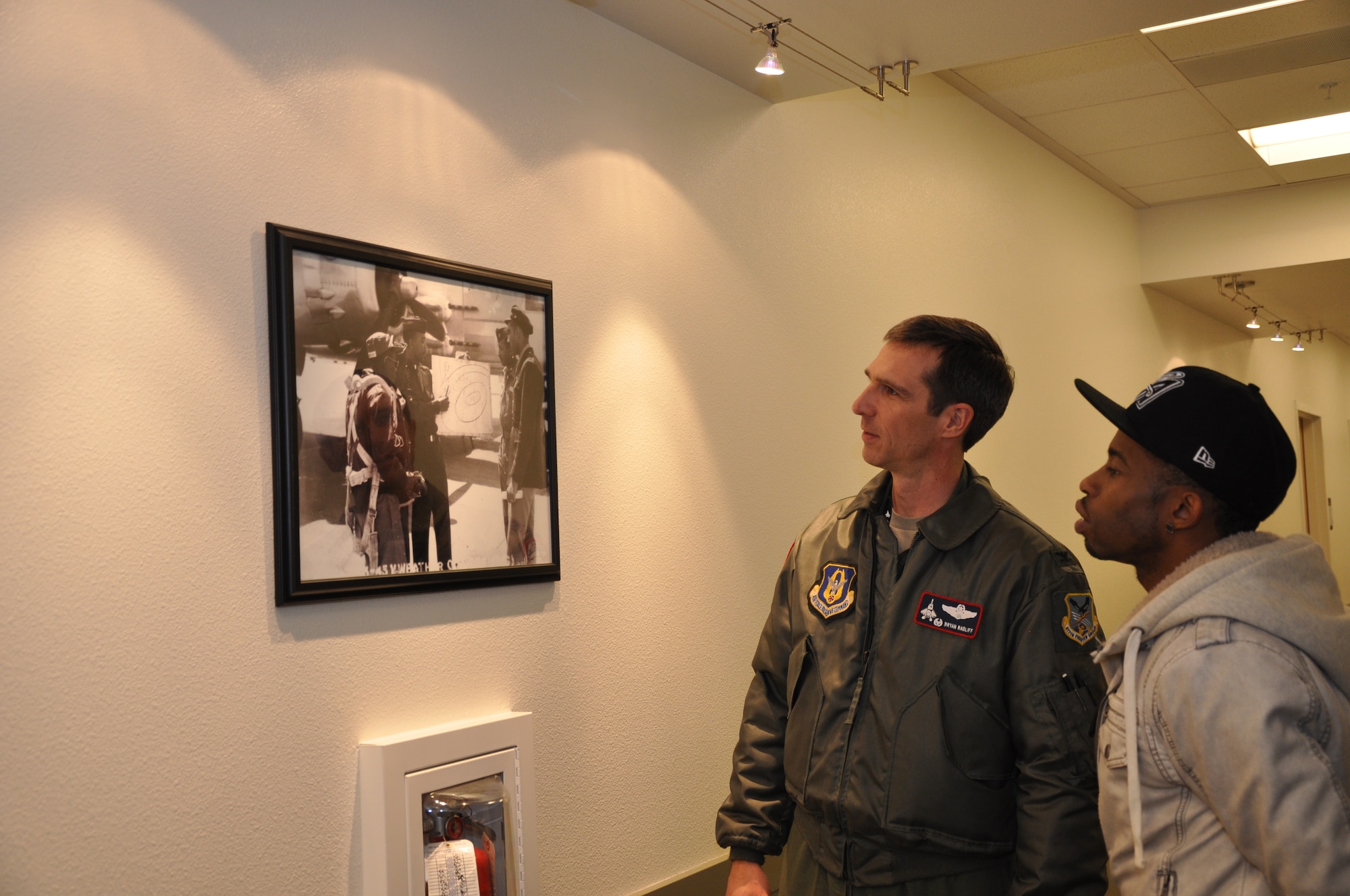 Col. Bryan Radliff, 477th Fighter Group commander, gives a tour of the 477th FG headquarters Tuskegee Airmen memorabilia to actor Marcus Paulk. Paulk plays Deke Watkins in the new George Lucas film, Red Tails, about the Tuskegee Airmen. An advanced screening was held for a small group of Reservists and Anchorage citizens Dec 15. (U. S. Air Force Photo/Capt. Ashley Conner)