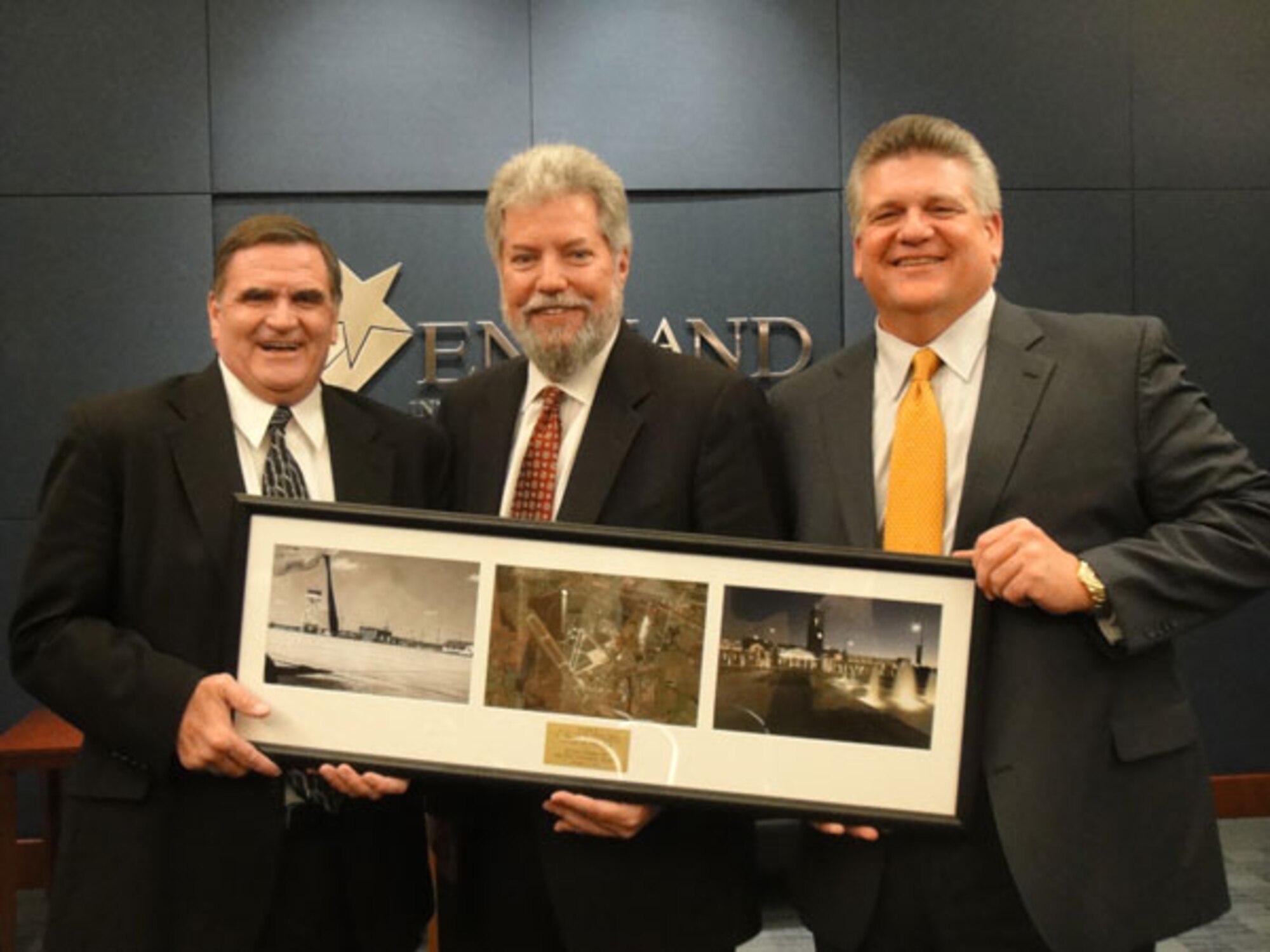Air Force Real Property Agency Director Robert Moore presents a commemorative photo to Lance Harris, Chairman of the England Authority and Jon Grafton, Executive Director of the England Authority during the Whole Base Transfer Ceremony on December 8, 2011.