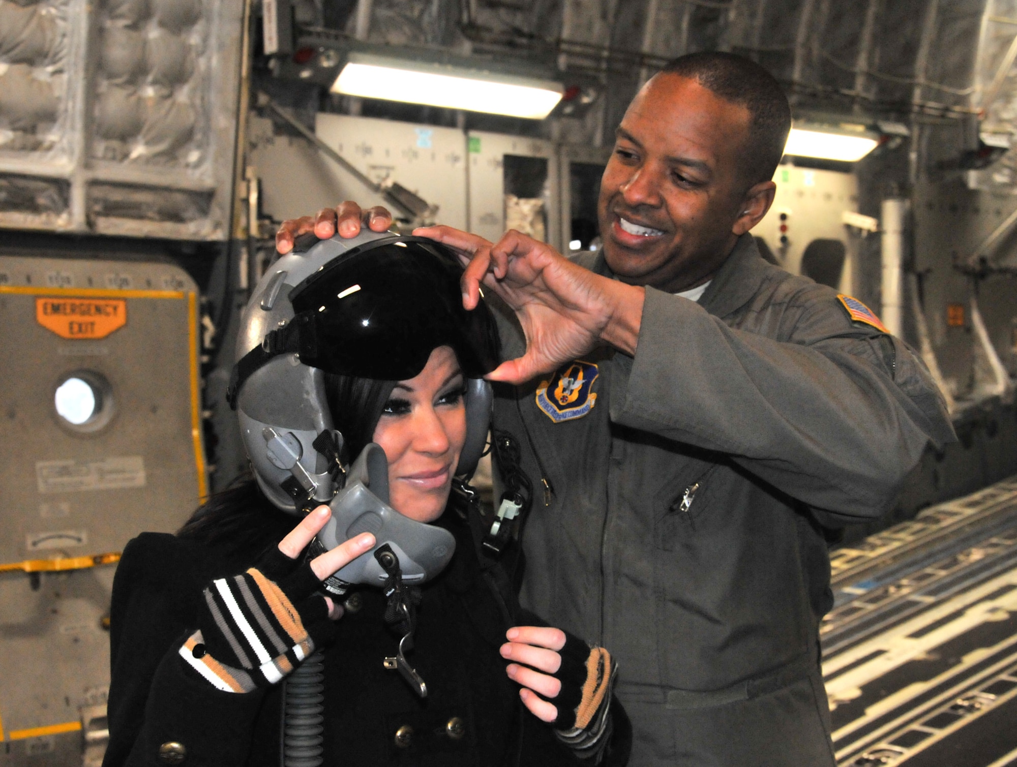 Senior Master Sgt. Derek Bryant (right), 728th Airlift Squadron senior loadmaster, McChord Field, Wash., dresses Total Nonstop Action wrestler Madison Rayne in aircrew gear on a C-17 Globemaster III, Dec. 6, 2011. Rayne and fellow wrestler Angelina Love visited JBLM to meet and greet the troops. During the C-17 tour, the ladies received an airlift briefing from Bryant and an aeromedical evacuation briefing from Reservists of the 446th Aeromedical Evacuation Squadron. (U.S. Air Force photo/2nd. Lt. Denise Hauser)