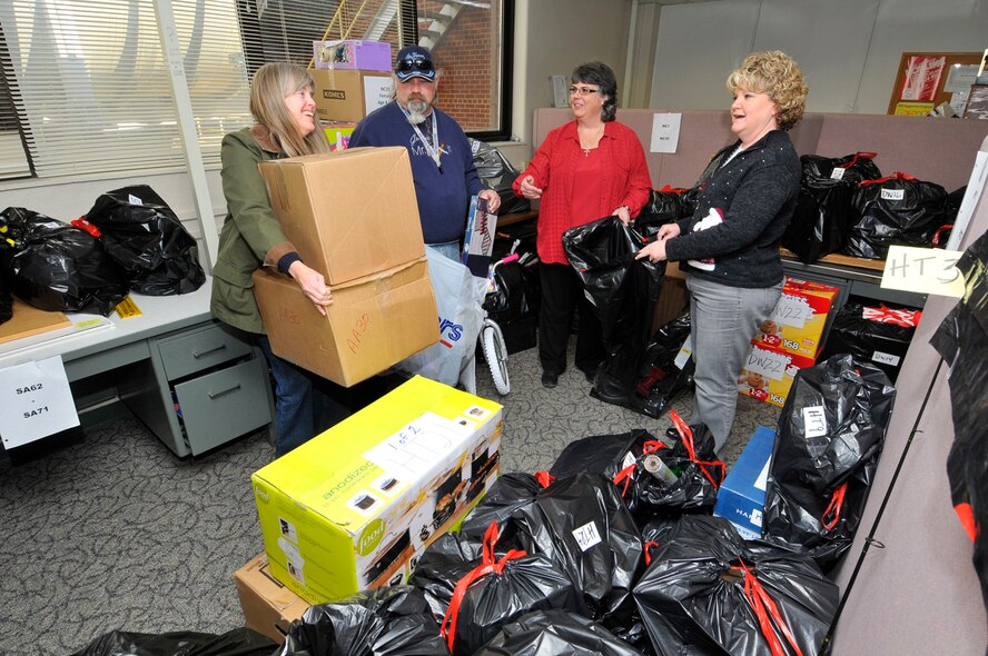 Pam King, of the Air Force Civil Engineer Branch, and Mitch Kendrick, an Aerospace Testing Alliance (ATA) power switchboard operator in Electrical Operation, drop off gifts for the Arnold Engineering Development Center (AEDC) Angel Tree as Janet Feller, coordinator of the program, and volunteer Lora Arnold assist. Feller, an information technologist, and Arnold, an engineering technician, are both members of the ATA Employee and Community Activity Committee (E&CAC), which is sponsoring the Angel Tree. Approximately 160 AEDC employees provided gifts to 179 disadvantaged children, who otherwise might not receive presents this Christmas. (Photo by Rick Goodfriend)