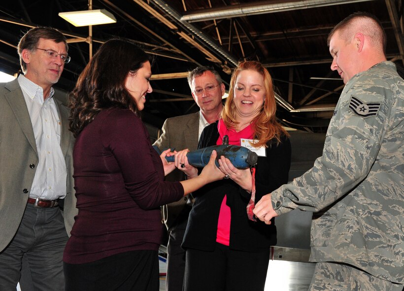 U.S. Air Force Staff Sgt. Daniel Grigg, 20th Maintenance Operations Squadron weapons standardization load crew chief, shows Kristen Villareal, (left center), and Leaigh-Ann Fabianke, (right center), Smith Associates risk communication support contractors, about the BDU-33 demonstration SUU-20 free-fall munitions and load drag munitions while Dr. Doug Cox, (left), Air Force Center for Engineering and the Environment toxicologist, and Michelle Kramer, (center), 20th Civil Engineer Squadron chief of environmental office, look on Dec. 15, 2011, Shaw Air Force Base, S.C. The demonstration was part of the Restoration Advisory Board workshop and base tour. (U.S. Air Force photo by Senior Airman Amber E. N. Jacobs/Released) 