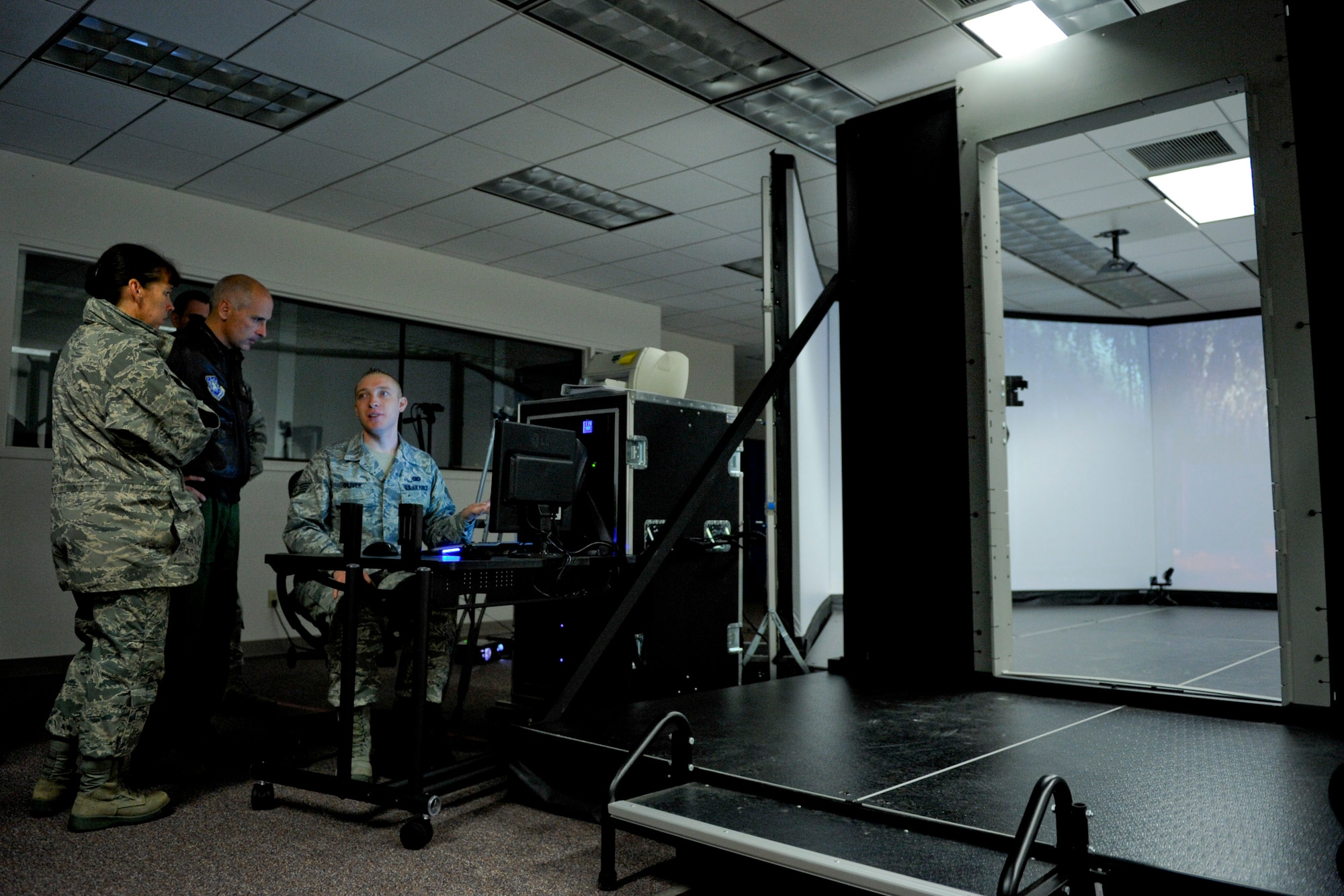 VANDENBERG AIR FORCE BASE, Calif. -- Staff Sgt. Andrew Oliver, a 30th Security Forces Squadron combat arms trainer, briefs Col. Richard Boltz, the 30th Space Wing commander, and Chief Master Sgt. Suzanne Talbert, the 30th SW command chief, on the 30th Security Forces Squadron's new firearms training simulator at Combat Arms here Thursday, Dec. 15th, 2011. The new simulator provides a virtual training environment for Vandenberg members to practice real world combat tactics and train with firearms qualification scenarios. (U.S. Air Force/Staff Sgt. Levi Riendeau)