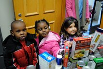 From left, Trellis Crusoe, Amayah Robinson and Makena Bliss of the Maxwell Child Development Center are among the children delivering canned goods to the Airman and Family Readiness Center's food pantry Tuesday. (Air Force photo/Christopher Kratzer)