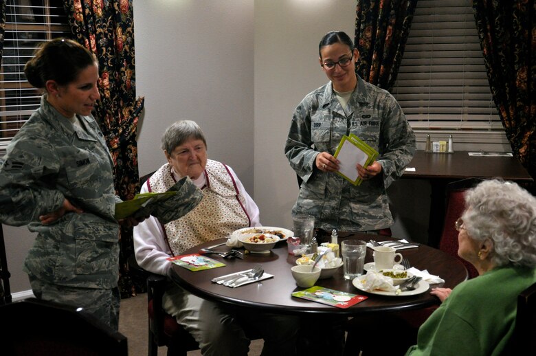 Airman 1st Class Stefanie Simon, 1st Special Operations Contracting Squadron, standing left, and Airman 1st Class Brandy Dirr, 1st Special Operations Wing Public Affairs, standing right, speak with residents after delivering holiday cards at the Air Force Enlisted Village's Hawthorne House in Shalimar, Fla., Dec. 13, 2011. Hurlburt Field Airman's Voice collected more than 500 individual signatures on the cards to be presented to the house's 64 residents. (U.S. Air Force photo/Staff Sgt. William Banton)(Released)