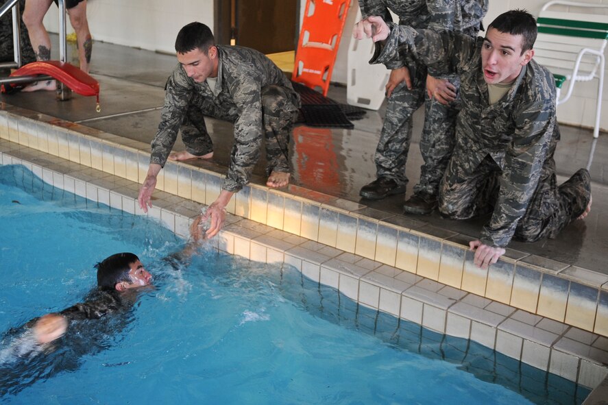 Members of the air liaison officer aptitude training assessment encourage teammates to complete a portion of a water confidence exercise at Moody Air Force Base, Ga., Dec. 14, 2011. The participants were involved in numerous activities that included swimming with their weapons and pushing their gear across the water while racing other groups. (U.S. Air Force photo by Airman Olivia Dominique/Released)