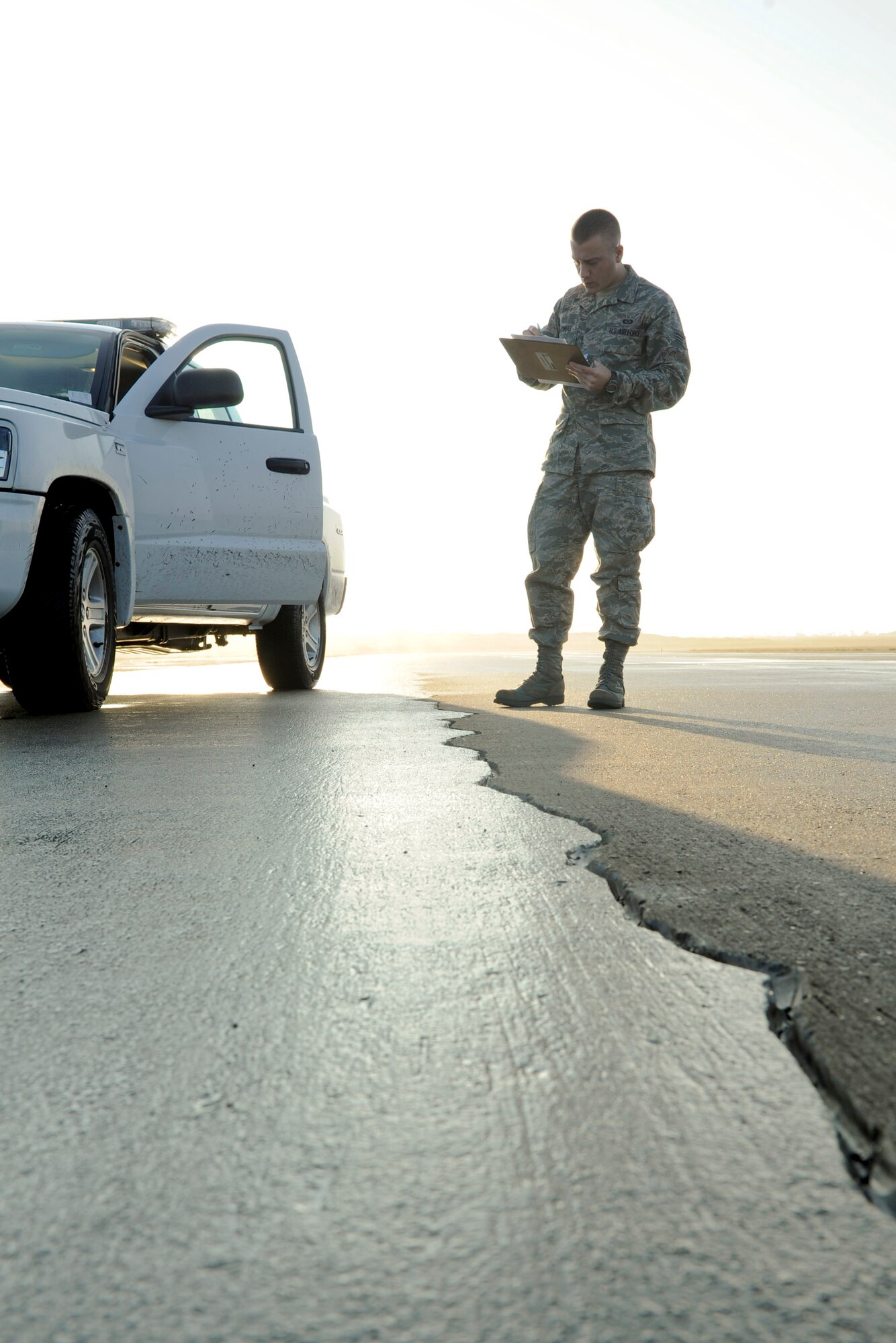 VANDENBERG AIR FORCE BASE, Calif. -- Senior Airman Christopher McComus, a 30th Operations Support Squadron airfield manager, notes a crack in the taxiway during the morning flightline inspection here Tuesday, Dec. 13, 2011. The Airfield Management team reviews broken equipment and cracks in the flightline to ensure that the airfield is ready to support operations at all times. (U.S. Air Force/Staff Sgt. Levi Riendeau)