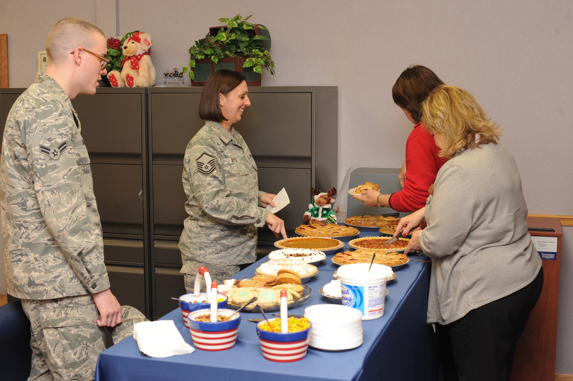 Airman 1st Class Patrick Davis, 22nd Comptroller Squadron special actions technician, and Master Sgt. Kim Byck, 22nd Maintenance Operations Squadron unit deployment manager, get free pie at the annual Airman and Family Readiness Center open house Dec. 14, 2011, McConnell Air Force Base, Kan. The open house was held to showcase the A&FRC’s fifty-plus programs available to Team McConnell. (U.S. Air Force photo/Airman 1st Class Jose L. Leon)