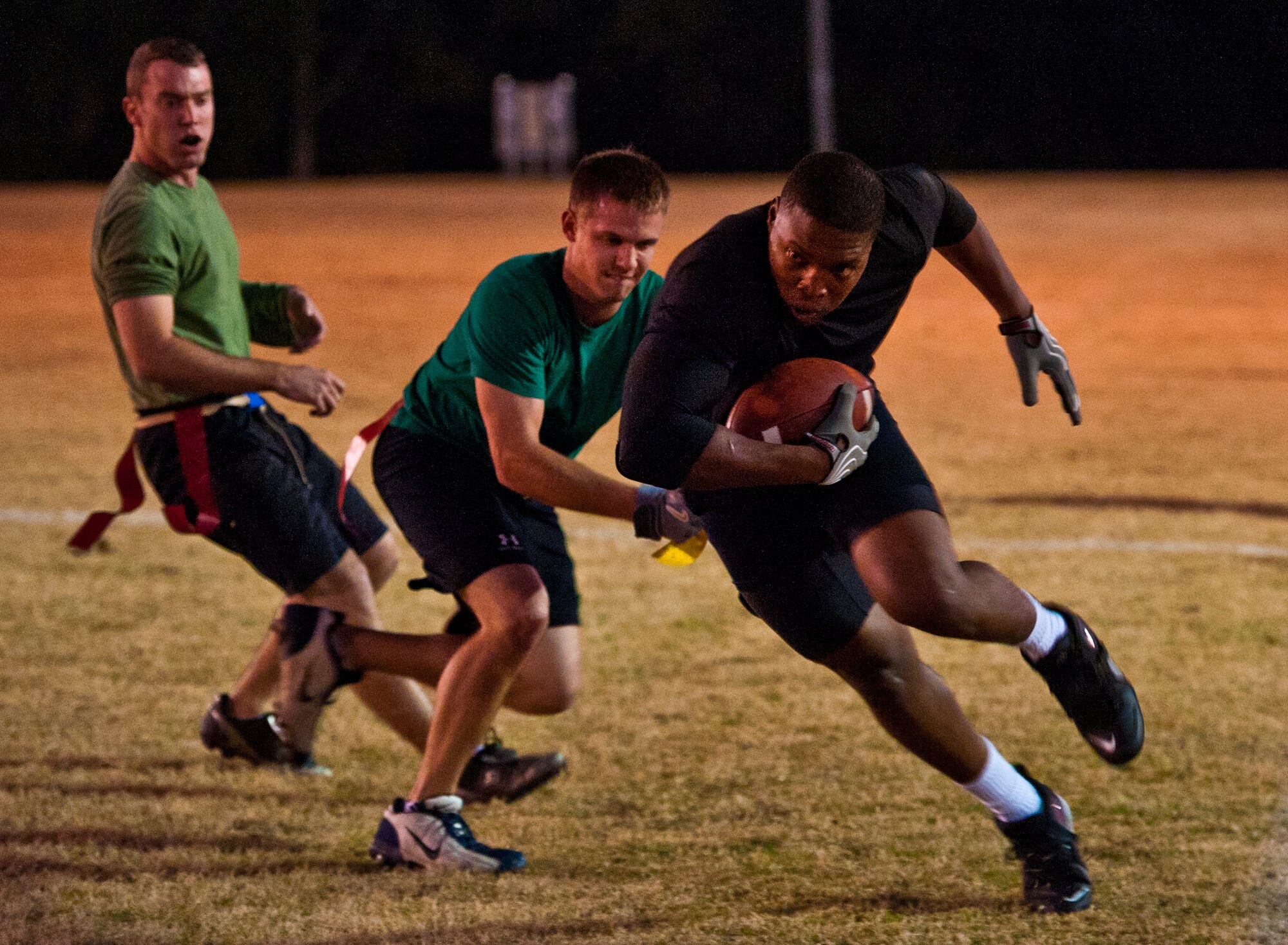 Zerrick Haymond, a 96th Security Forces Squadron wide receiver, passes by two Air Armament Center defenders during the base intramural flag football championship game Dec. 15 at Eglin Air Force Base, Fla.  SFS beat the Air Armament Center team 19-14 to claim the title.  It had been three years since they’d been the champs.  (U.S. Air Force photo/Samuel King Jr.)