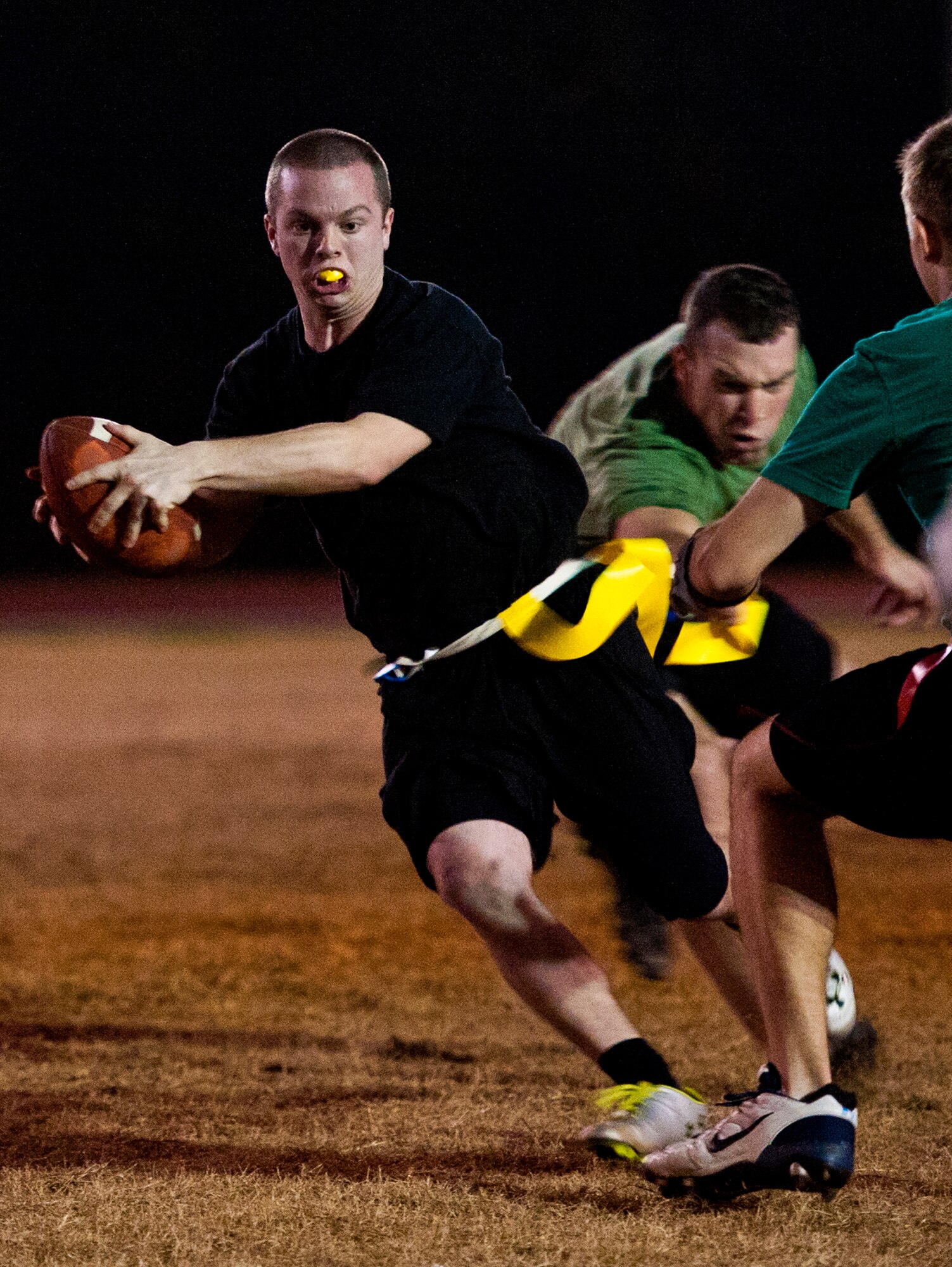 Josh Ballard, a 96th Security Forces Squadron player, runs by Air Armament Center defenders during the base intramural flag football championship game Dec. 15 at Eglin Air Force Base, Fla.  SFS beat the Air Armament Center team 19-14 to claim the title.  It had been three years since they’d been the champs.  (U.S. Air Force photo/Samuel King Jr.)