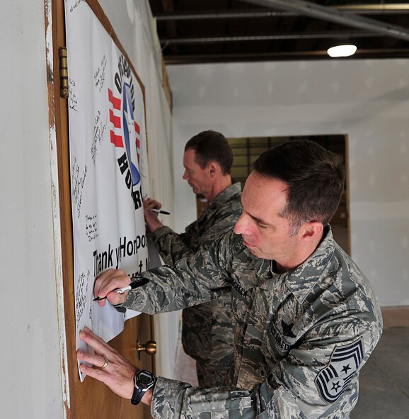 MINOT AIR FORCE BASE, N.D. -- Col. James Dawkins, 5th Bomb Wing commander and Chief Master Sgt. Kevin Jurgella, 5th BW command chief, sign an Operation Homefront thank you banner here Dec. 15. This is part of Operation Homefront, a charitable initiative, headed by the Home Depot Foundation, in coordination with Minot AFB’s Operation Warm Heart and General Electric, to donate more than 130 appliances to Team Minot Airmen and their families affected by the historic Souris River flood. (U.S. Air Force photo/Senior Airman Desiree Esposito)