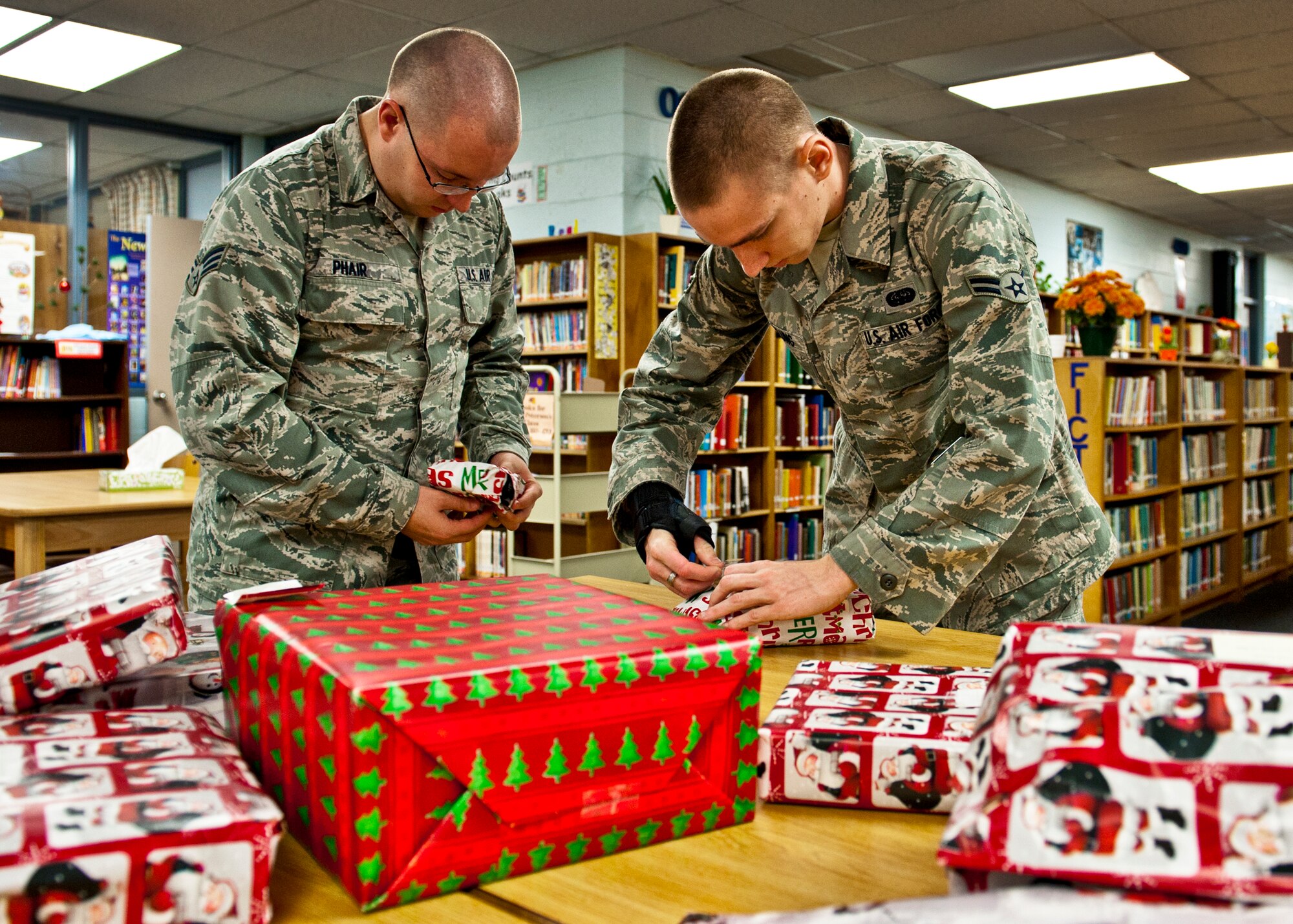 Senior Airman Adam Phair and Airman 1st Class Charles McClung, of the 46th Operations Group, finish wrapping gifts for their adopted family Dec. 15 at Bruner Middle School.  Squadrons from the 46th Operations Group adopted 14 needy families from the school and provided them with food and gifts for the holidays.  (U.S. Air Force photo/Samuel King Jr.)