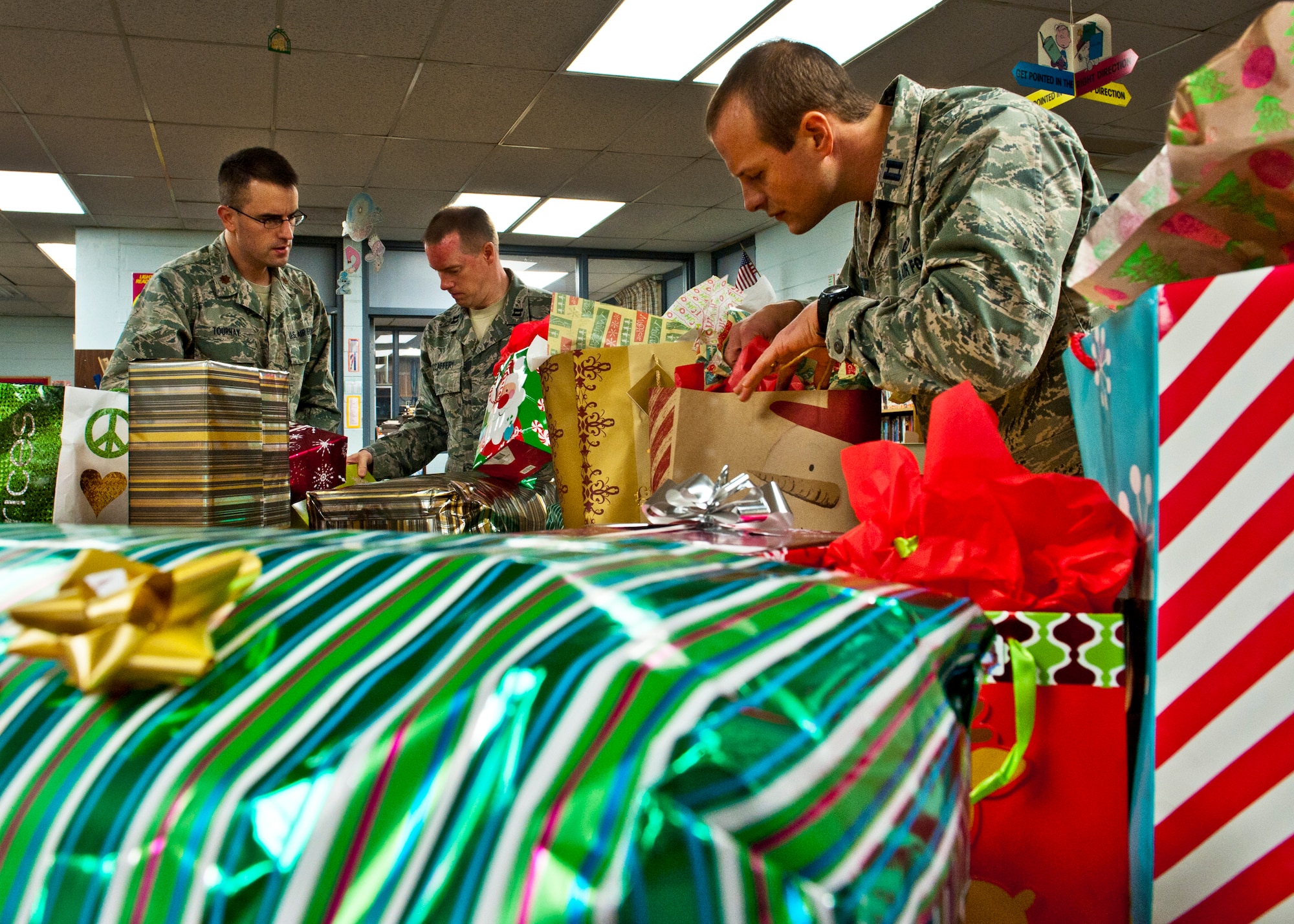Maj. Robert Tournay, Capt. Donald McCaffery and Capt. Doug Oltmer, of the 46th Weather Flight, set out gifts for their adopted family Dec.15 at Bruner Middle School.  Squadrons from the 46th Operations Group adopted 14 needy families from the school and provided them with food and gifts for the holidays.  (U.S. Air Force photo/Samuel King Jr.)