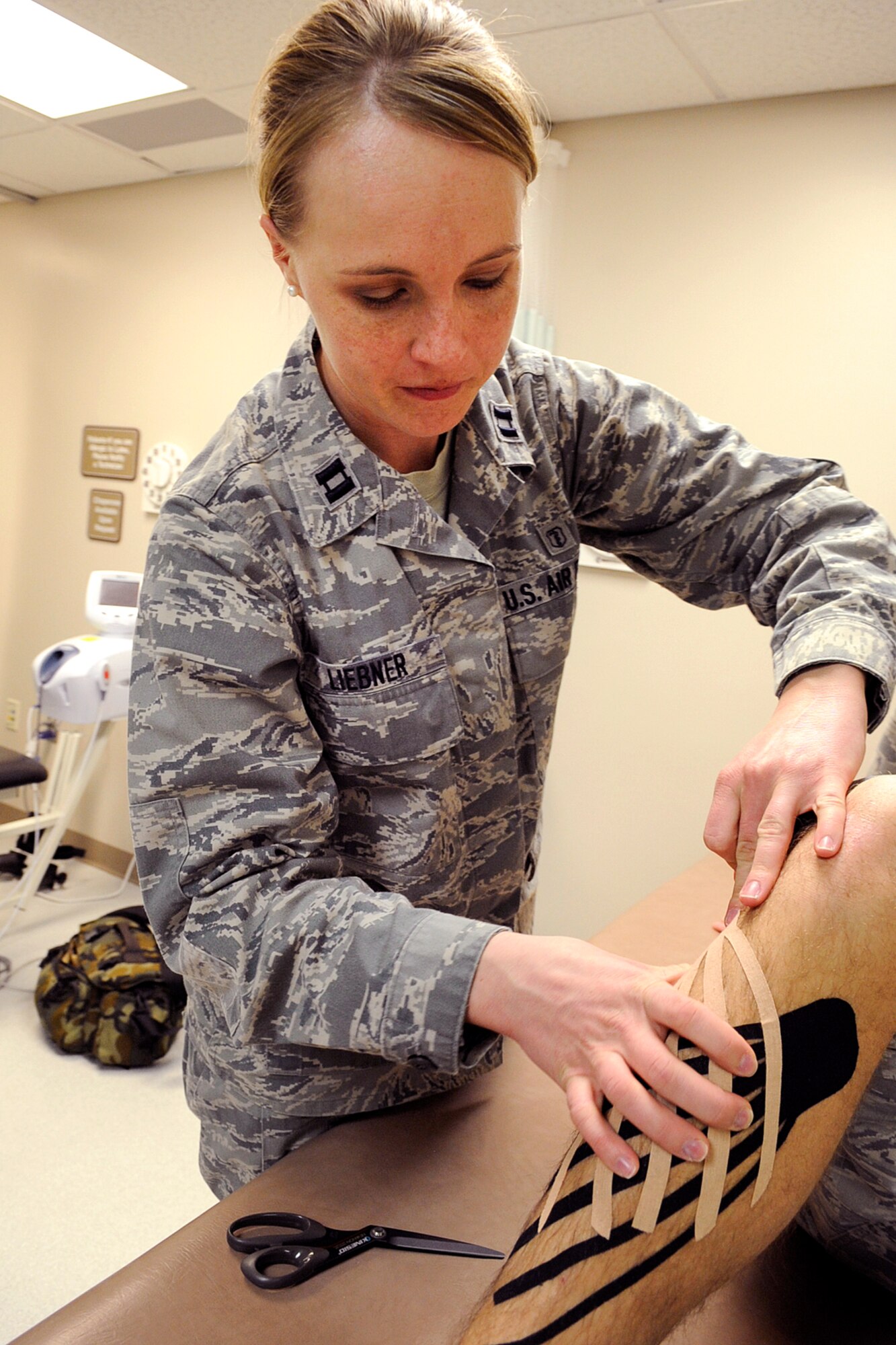 Capt. Elizabeth Liebner, 21st Medical Group, applies Kinesio Tape to a patient’s leg Dec. 14 at the physical therapy clinic. The tape is applied to muscles and promotes natural healing through stimulation of the circulatory and neurological systems. In October, the entire 21st Medical Group Physical Therapy clinic team traveled to Phoenix to become the first-ever fully certified Air Force team in Kinesio Taping. (U.S. Air Force photo/Rob Bussard)