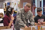 Staff Sgt. Joshua Clements, 902nd Security Forces Squadron, and Schlather Intermediate School sixth-graders, (from left) Isabelle Aimone, Mykiah Ausby and Nick Fulbright participate in Operation Shoebox Dec. 9 by preparing holiday care packages to be mailed to deployed Joint Base San Antonio service members. 
(U.S. Air Force photo by Airman 1st Class Alexis Siekert)