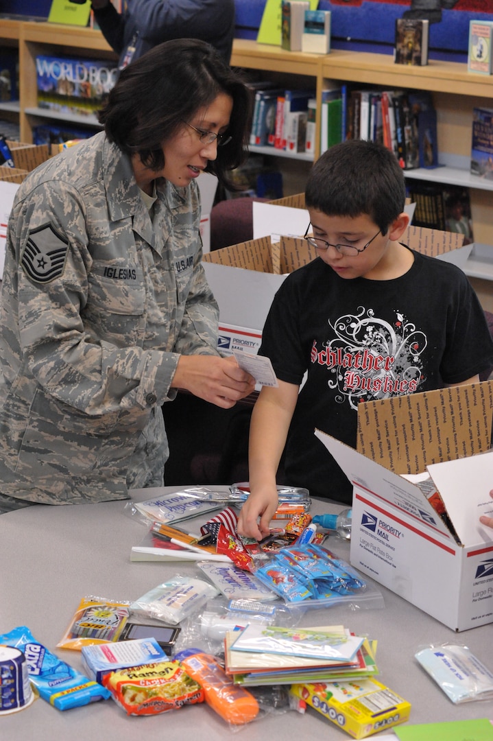 Master Sgt Karla Iglesias, Airman and Family Readiness Center NCO in charge, works with Matthew Avila, Schlather Intermediate School fifth-grader, to put together care packages for 35  deployed Joint Base San Antonio servicemembers. Through Operation Shoebox, the students were able to send packages spreading holiday cheer to deployed troops
(U.S. Air Force photo by Airman 1st Class Alexis Siekert)