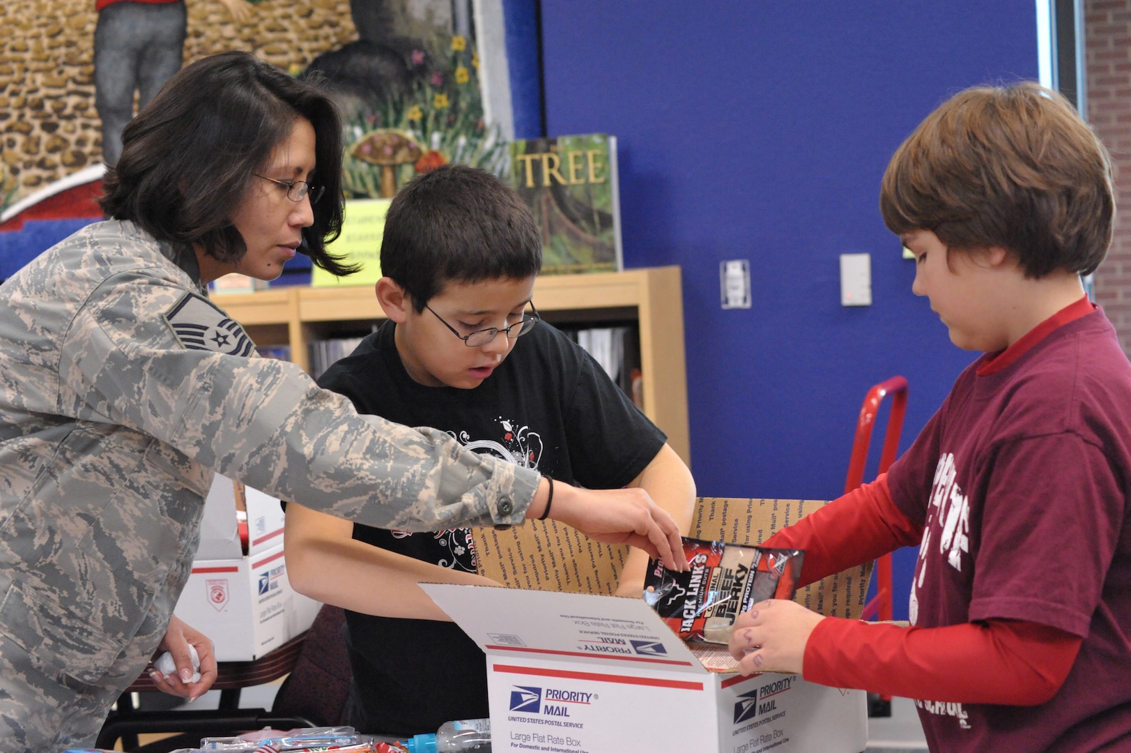 Master Sgt Karla Iglesias, Airman and Family Readiness Center NCO in charge, works with Matthew Avila, Schlather Intermediate School fifth-grader, to put together care packages for 35  deployed Joint Base San Antonio servicemembers. Through Operation Shoebox, the students were able to send packages spreading holiday cheer to deployed troops
(U.S. Air Force photo by Airman 1st Class Alexis Siekert)