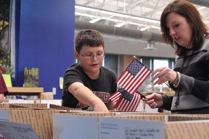 Carter Arispe, Schlather Intermediate School sixth-grader, and Carla Barnes, Schlather counselor, participate in Operation Shoebox Dec 9 by placing American flags into each care package to be sent to deployed Joint Base San Antonio servicemembers over the holidays.
(U.S. Air Force photo by Airman 1st Class Alexis Siekert)
