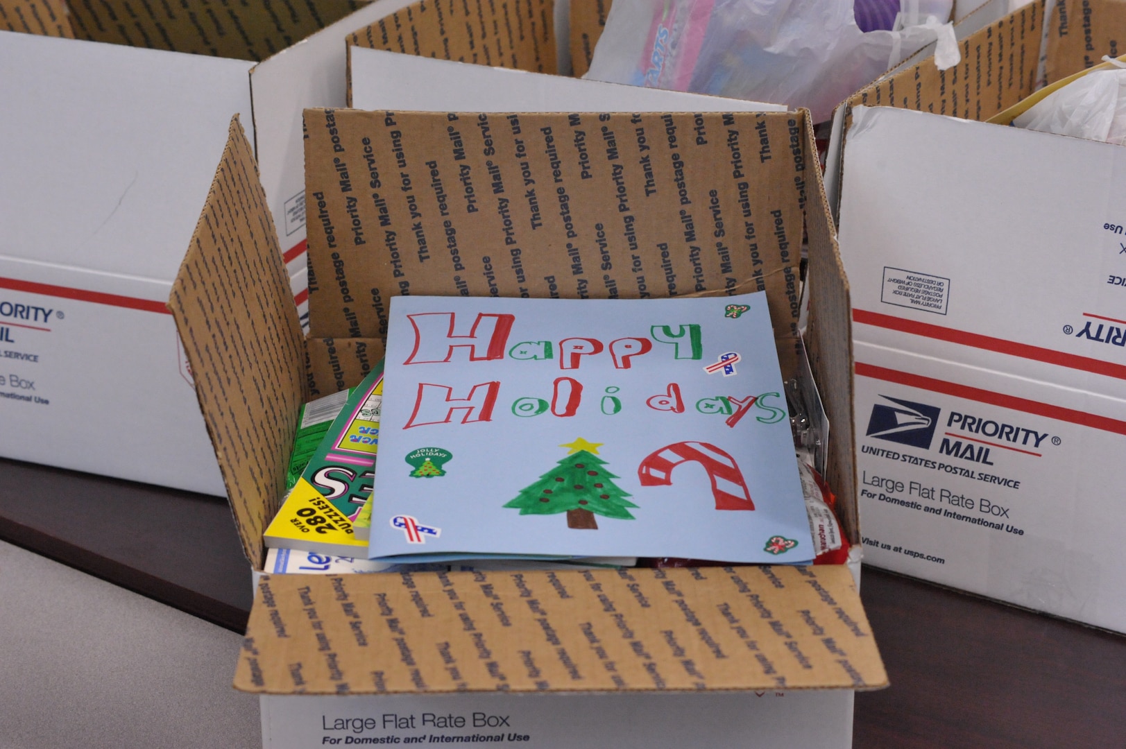 A handmade holiday card sits on top of a care package put together by Schlather Intermediate School's fifth and sixth grade students during Operation Shoebox Dec 9.(U.S. Air Force photo by Airman 1st Class Alexis Siekert)