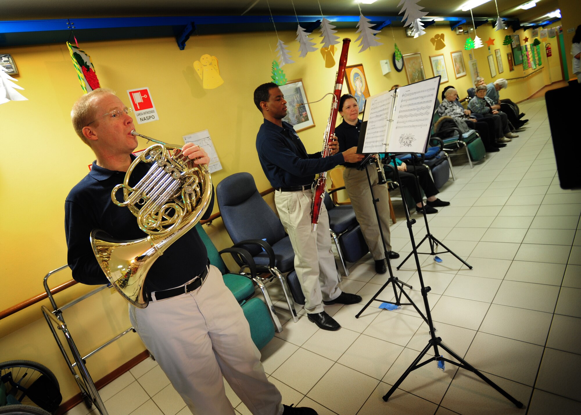 (From Left) Master Sgt. Steven Schaughency, Staff Sgt. Jerome Minor, and Tech. Sgt. Shannon Dooley, members of U.S. Air Forces in Europe Band Winds Aloft Woodwind Quintet, perform at a nursing home Dec. 16 in San Quirino, Italy. The ensemble serenaded Team Aviano and the local community members with holiday music Dec. 14-16 as part of a community relations tour celebrating the holidays. (U.S. Air Force photo/Staff Sgt. Evelyn Chavez) 