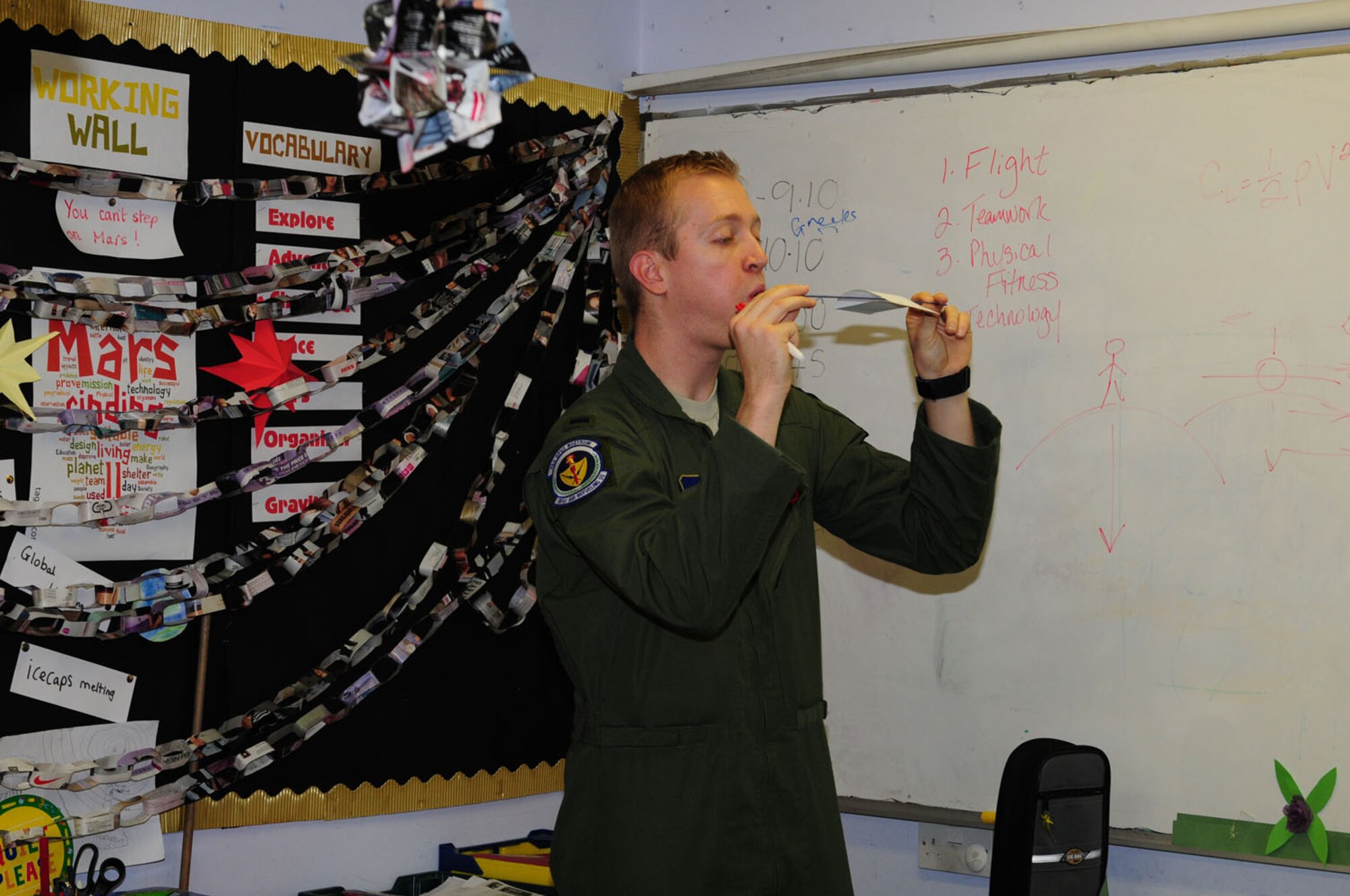 MILDENHALL, England – 1st Lt. Mark Watson, 351st Air Refueling Squadron pilot,  demonstrates to children from Great Heath Primary School the principles of lift and pressure, and what happens when air goes over an aircraft’s wings Dec. 6, 2011. The RAF Mildenhall pilot visited the school as part of their Space Week celebrations and talked to them about the history of aviation, as well as giving them the chance to take part in teambuilding exercises and experiments, and watch video of a space shuttle launch and lunar pod landing. (U.S. Air Force photo/Karen Abeyasekere)