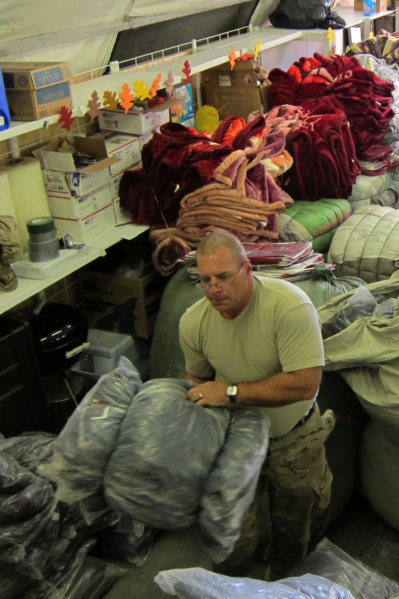 Army Sgt. Kent Christiansen sorts jackets at the Transit Center at Manas, Kyrgyzstan, Dec. 14, 2011, that will be given to Kyrgyz citizens as part of Operation Warm and Dry. A group of Airmen and Soldiers processed more than 3,600 jackets and 500 blankets worth $102,000 that will soon be delivered to Kyrgyz citizens. Christiansen is deployed here as an Army liaison officer from Fort Drum, N.Y. (U.S. Air Force photo/ Senior Master Sgt. Mark Redden)