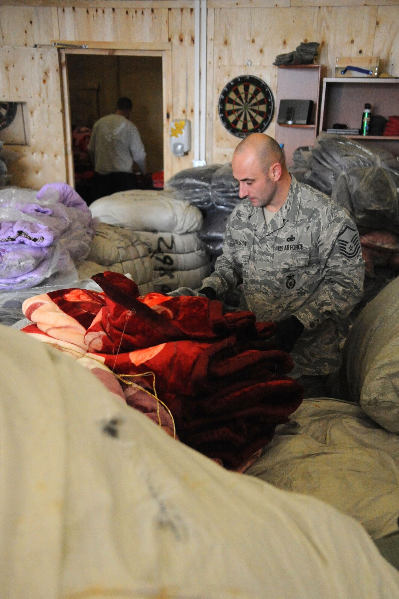 Master Sgt. Sam Nelson sorts jackets and blankets at the Transit Center at Manas, Kyrgyzstan, Dec. 14, 2011, that will be given to Kyrgyz citizens as part of Operation Warm and Dry. Operation Warm and Dry is a humanitarian assistance project designed to provide jackets and blankets for children and elderly adults in the Kyrgyz Republic, where the winters are extreme. Nelson is deployed to the Theater Security Cooperation division as the NCO in charge of humanitarian assistance from Bellows Air Force Station, Hawaii. (U.S. Air Force photo/Tech. Sgt. Tammie Moore)