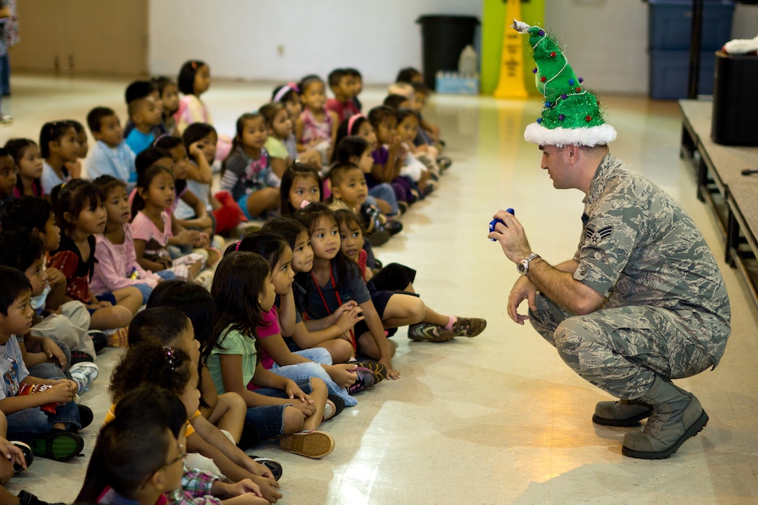 YIGO VILLAGE, Guam -- Senior Airman William Pressgrove, Band of the Pacific-Asia vocalist, shows photos of his children to students at the Machanano Elementary School, Yigo Village, Guam, Dec. 13, 2011. Pressgrove did this to help connect with his young audience members. (U.S. Air Force photo/Staff Sgt. Josh Voyles)