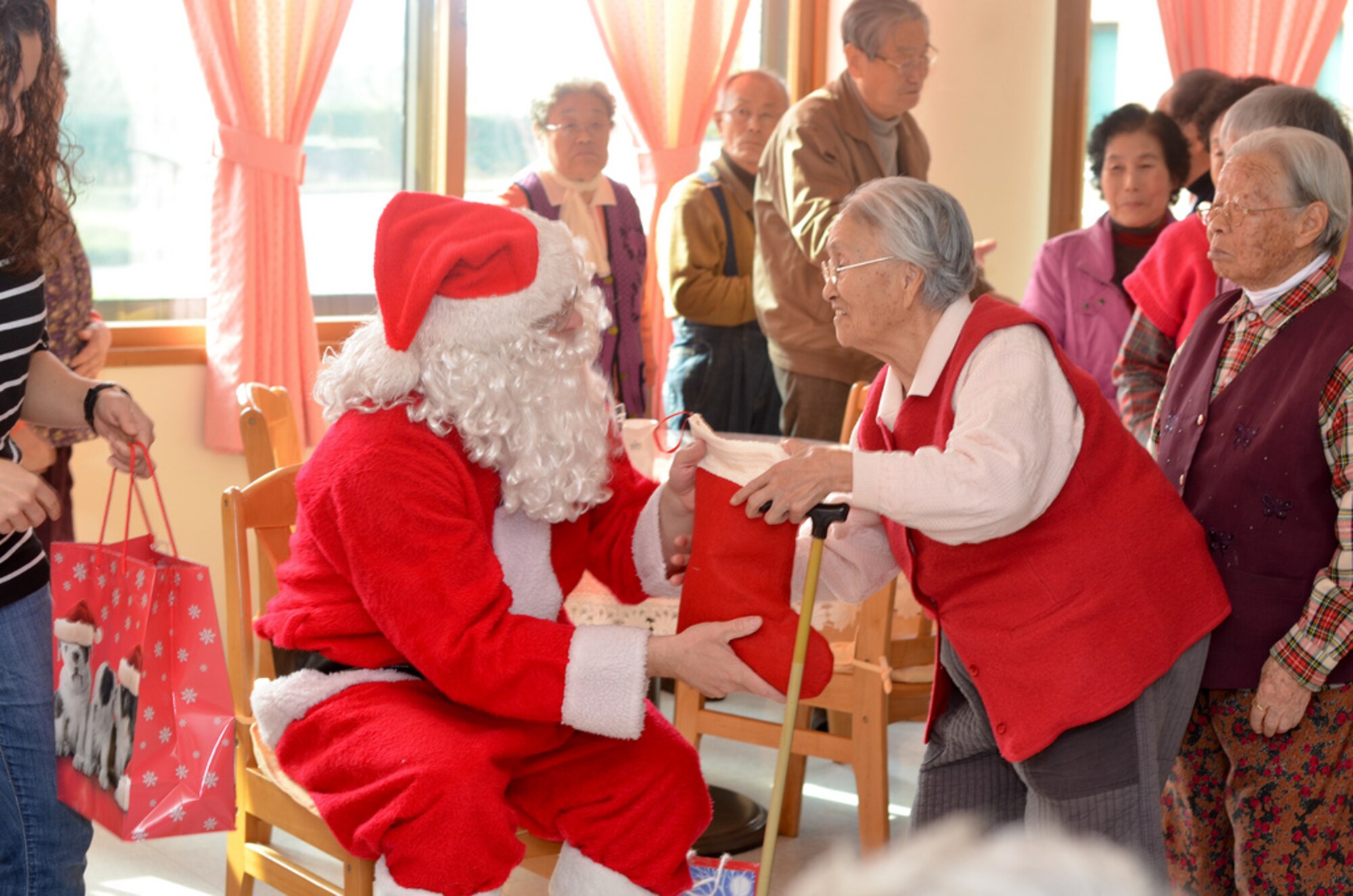 A member of the Wolf Pack dressed as Santa Claus, gives a stocking to a resident of the Heart of Jesus Senior Care elderly home during his visit there for a Christmas celebration in Gunsan City, Republic of Korea, Dec. 10, 2011. The senior center was host to many smiles, cake, joint decorating and singing classic Christmas carols. (U.S. Air Force photo by Senior Airman Derrick Schwieters/Released)