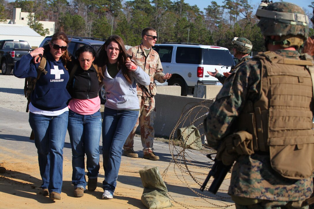 Role players carrying a wounded civilian approach a notional American Embassy during a Non-Combatant Evacuation Operation training scenario as part of the Composite Training Unit Exercise (COMPTUEX), Dec. 16. The operation, called NEO for short, is meant to evacuate American citizens and other authorized personnel from a country in turmoil.  The 24th MEU just completed COMPTUEX, which took place Nov. 28 to Dec. 20. The training served to develop cohesion between the 24th MEU and Amphibious Squadron 8 (PHIBRON 8) in conducting amphibious operations, crisis response, and limited contingency operations while operating from the sea.