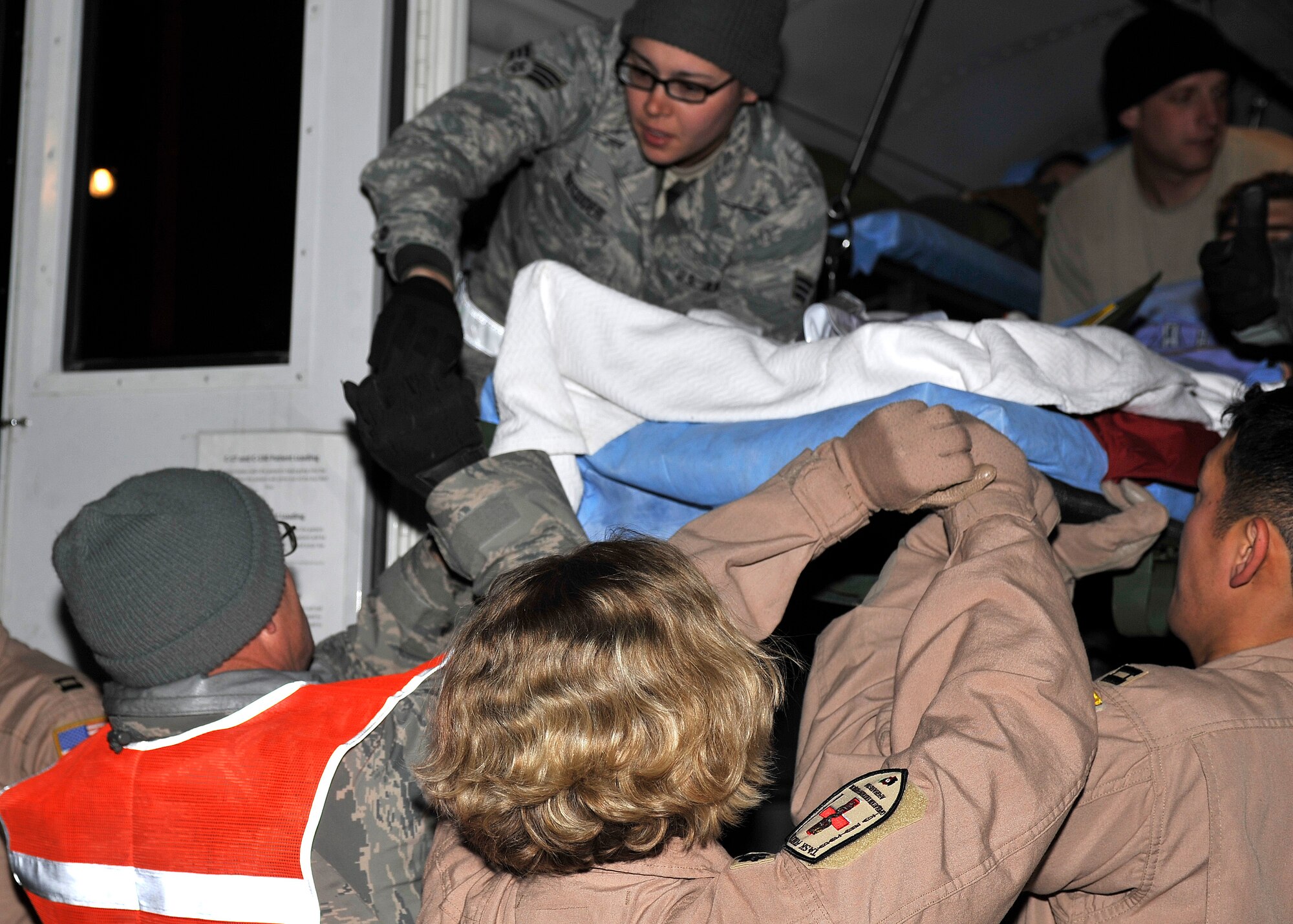BAGRAM AIRFEILD, Afghanistan -- Senior Airman Danielle Recoder, medical technician with the 455th Expeditionary Medical Group, works with volunteers to load a patient onto an ambulance bus at Bagram Airfield, Afghanistan, Dec. 14, 2011. Recoder is a part of the Contingency Aeromedical Staging Facility, which is responsible for the transportation of patients at Bagram Airfield. (U.S. Air Force photo/Airman 1st Class Ericka Engblom)