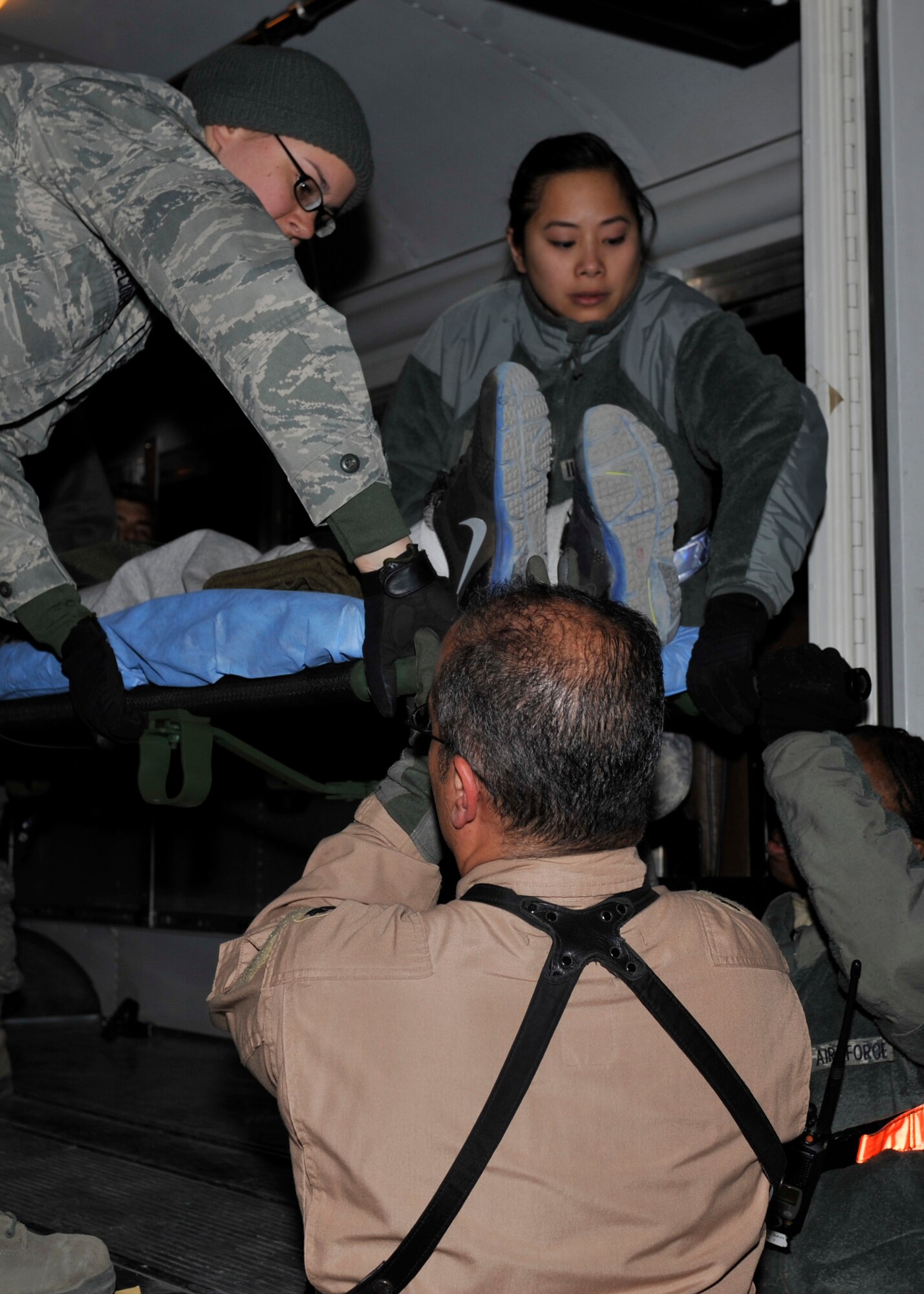 BAGRAM AIRFEILD, Afghanistan -- Senior Airman Danielle Recoder, medical technician, and Tech. Sgt. Leslie Landero, Non-commissioned Officer in Charge of the Contingency Aeromedical Staging Facility, assist in lifting a patient onto an ambulance bus during a medical transport at Bagram Airfield, Afghanistan, Dec. 14, 2011. The CASF consists of a multitude of medical professionals and volunteers responsible for the transportation of patients to and from Craig Joint Theater Hospital. (U.S. Air Force photo/Airman 1st Class Ericka Engblom)