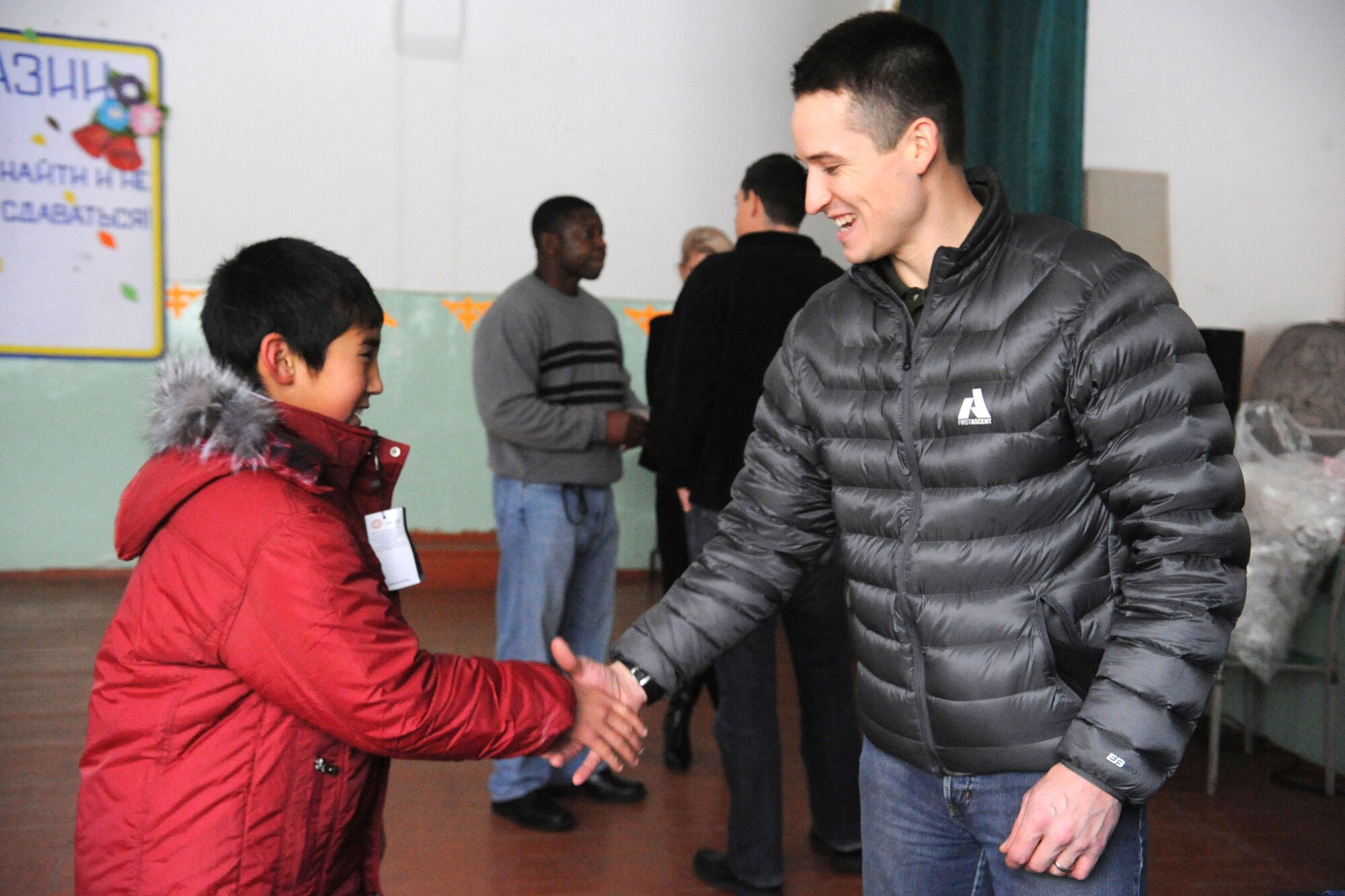 A student at the Manas Village School, Kyrgyzstan, thanks Capt. Spencer Bowen for his new jacket Dec. 17, 2011. The boy is one of 19 students at the school who received new winter jackets through the Transit Center at Manas’ Operation Warm and Dry Program. Bowen is a 376th Air Expeditionary Wing Theater Security Cooperation humanitarian assistance project officer deployed from the University of Washington ROTC Detachment 910 in Seattle. (U.S. Air Force photo/Tech. Sgt. Tammie Moore)    