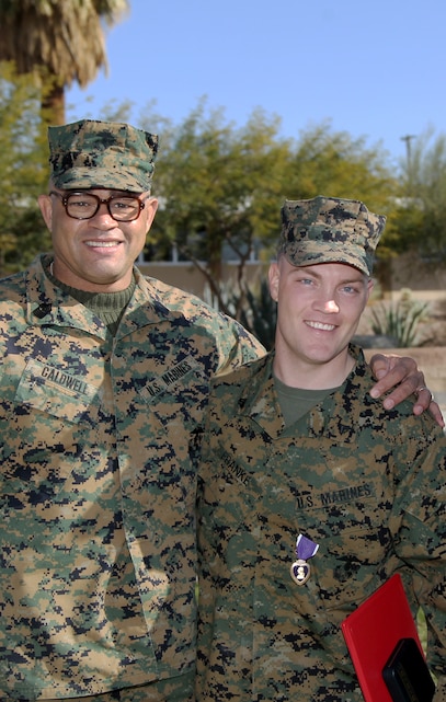 Cpl. Daniel J. Franke, K9 handler, Company A, Headquarters Battalion, smiles with Sgt. Maj. Robert Caldwell, III Marine Headquarters Group, III Marine Expeditionary Force, sergeant major, after Franke was awarded the Purple Heart Medal Dec. 15, 2011. Franke’s parent command is IIII MHG, III MEF.