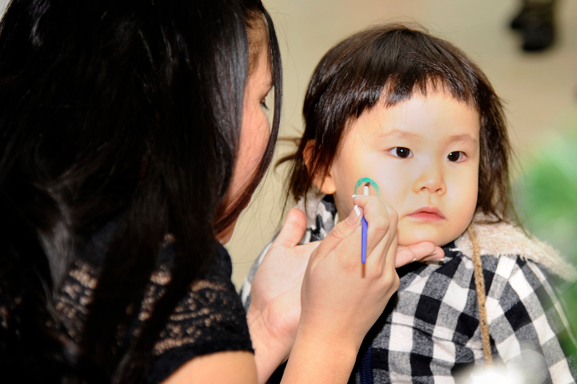 MISAWA AIR BASE, Japan - Staff Sgt. Stephanie Maya, 35th Aerospace Medicine Squadron, face paints a holiday design on Koharu Okudera during the Misawa Holiday Lights Tour here, Dec. 17. Japanese guests from the local community listened to holiday music and enjoyed holiday lights on display. Children enjoyed drawing pictures, making holiday ornaments, face paintings and balloon animals. (U.S. Air Force photo/Tech. Sgt. Marie Brown)