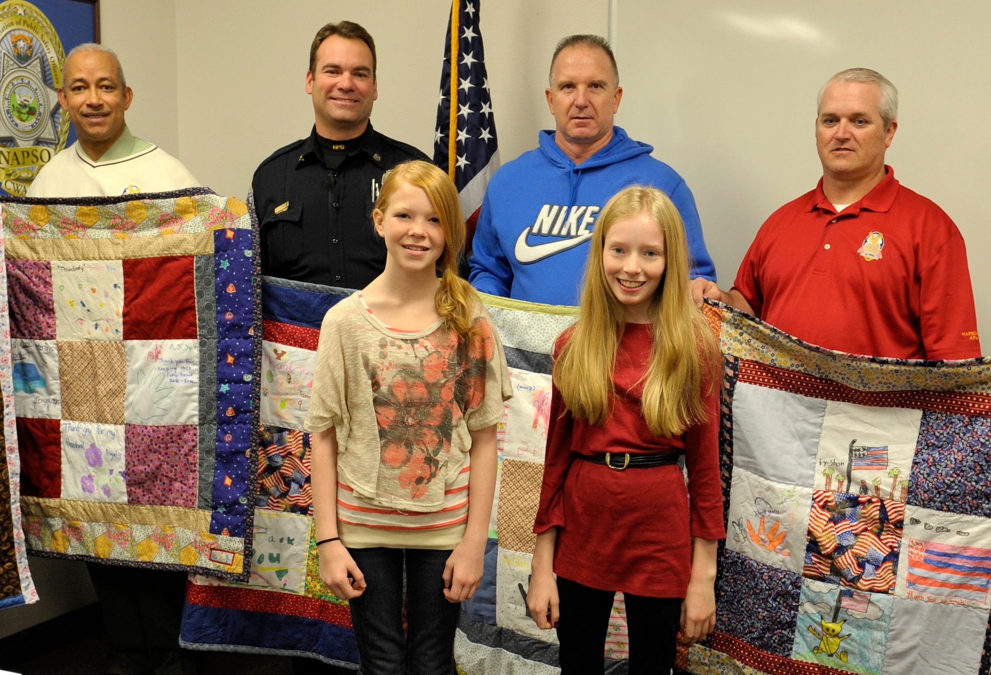 Katelyn Robinson and Abigail Leavitt, both 11 years old, pose with veterans who are now policemen and their quilts Dec. 16, 2011, in Henderson, Nev. Leavitt and Robinson donated these quilts on behalf of the local organization, Moms Love Quilts, which distributed more than 1,000 quilts to veterans and active duty service members in 2010. Currently attempting to gain 501(c)3 status, the organization has received donations from as far away as San Diego, Calif., and has donated quilts to locations as far-reaching as Wyoming. (U.S. Air Force photo by Benjamin Newell/Released)