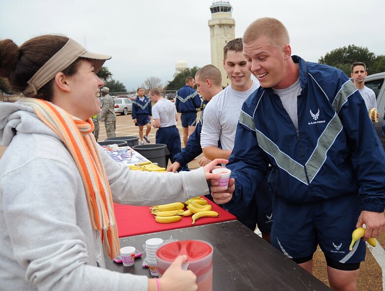 Amanda Nelson, Smoothie King employee, hands a sample smoothie to Senior Airman Tony Murphy, 2nd Operations Support Squadron, after the Ham Haul Fun Run Dec. 16 at the flightline on Barksdale Air Force Base, La. Several sponsors supported the wing fun run with snacks, hydration and prizes which were raffled off after the run. Sponsors included Barksdale Federal Credit Union, T-Mobile, Splash Kingdom and Smoothie King. (U.S. Air Force photo/Senior Airman Amber Ashcraft)(RELEASED)