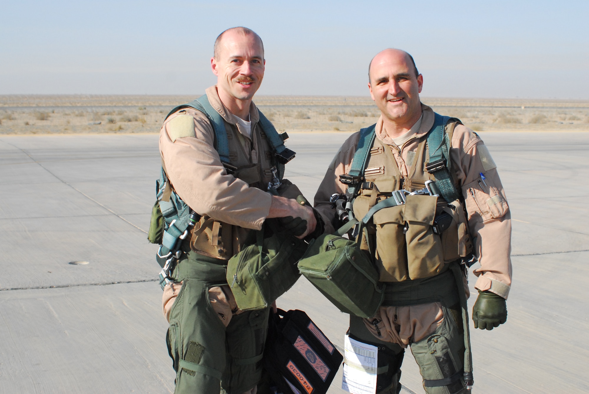 Lt. Col. Jason Plourde, 79th Expeditionary Fighter Squadron commander and Col. Rodney Petithomme, 332nd Expeditionary Operations Group commander, shake hands after flying the last two combat aircraft over Iraq Dec. 18, 2011. Piloting F-16s, they provided top cover for the last convoys leaving the country. Petithomme is a native of Angels Camp, Calif., and is deployed from Osan Air Base, Republic of Korea. Plourde is a native of Hermon, Maine, and is deployed from Shaw Air Force Base, S.C. (U.S. Air Force photo/1st Lt. Rusty Ridley)