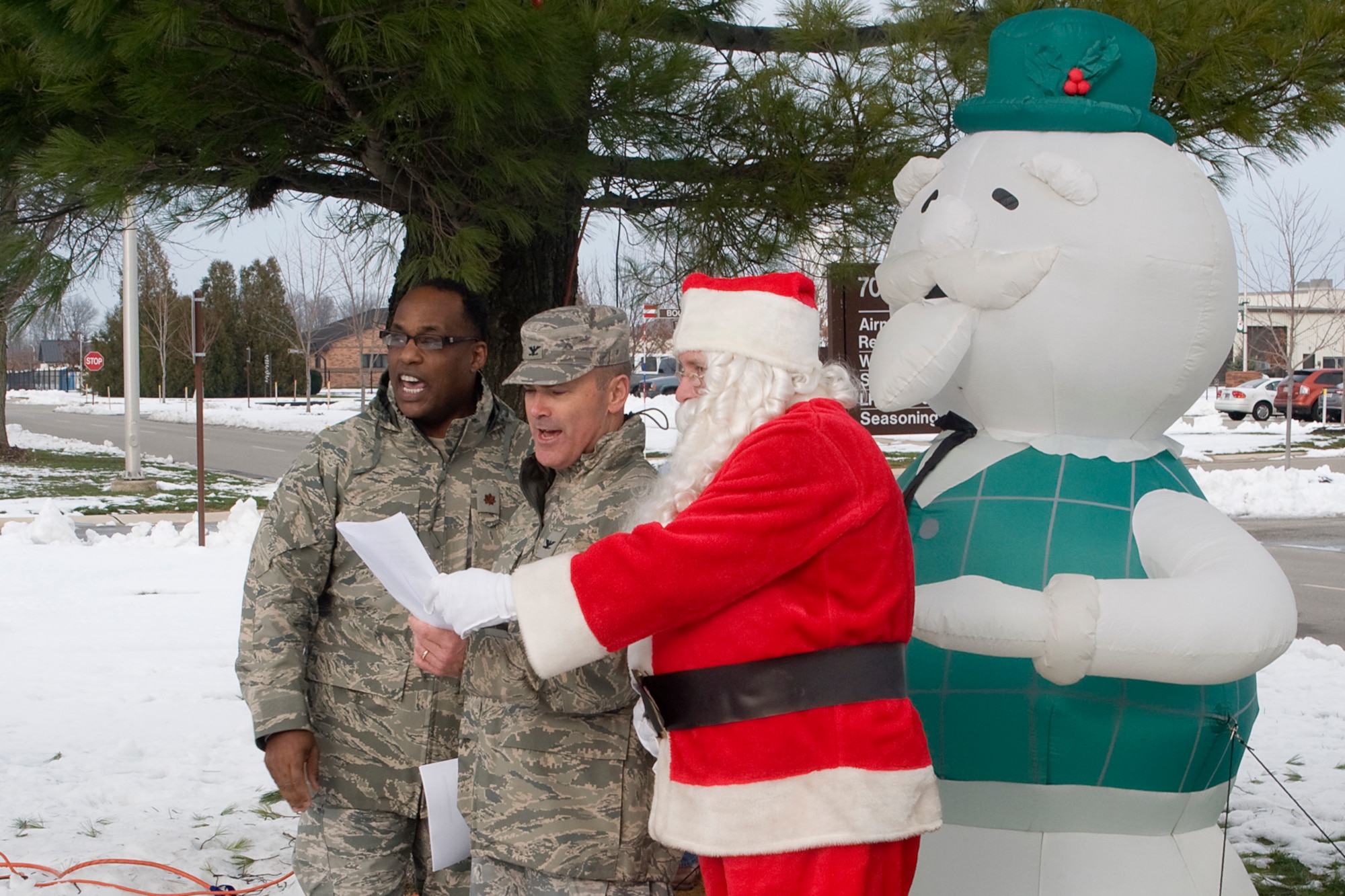 GRISSOM AIR RESERVE BASE, Ind. -- From left to right, Chaplain (Maj.) Obadiah Smith, Col. William T. "Tim" Cahoon and Santa Claus sing Oh Christmas Tree under  outside the Airman and Family Readiness building under a white pine tree, which was lit up for the holidays during the December unit training assembly. Cahoon is the 434th Air Refueling Wing Commander and Smith is the 434th ARW chaplain. (U.S. Air Force photo/Senior Airman Andrew McLaughlin)
