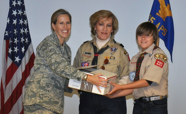 Lt. Col. Vanessa Dornhoefer, commander of the 25th Aerial Port Squadron (left), accepts one of several care packages prepared for deployed members and delivered by memberso of Boy Scout Troop 220 of Alabaster, Ala., represented by Troop Master Wanda Byrd and Webelo Scout Cole Holcomb.