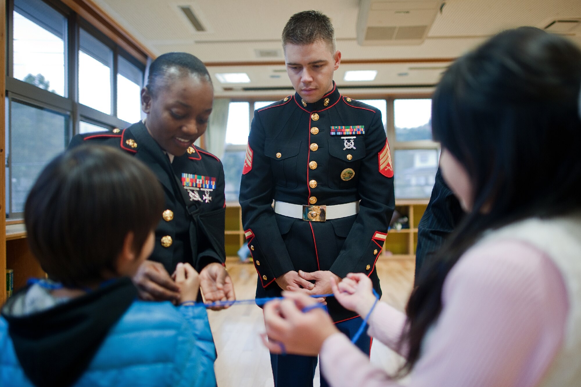 AKIRUNO CITY, Japan -- (left to right) Sgt. Stacian Manglay and Sgt. Timothy Johnston, both from U.S. Forces Japan, play a game of "Cat's Cradle" after delivering Christmas gifts to the children of the Ajiro Orphanage, Akiruno City, Tokyo, Japan, Dec. 16, 2011. Toys for Tots is a U.S. Marine Corps Reserve program that is designed for the collection of new, unwrapped toys during October, November and December each year, for distribution of those toys as gifts to needy children in the community during the holiday season. Marines at Yokota AB distributed the toys collected to children at local orphanages. (U.S. Air Force photo/Osakabe Yasuo)   