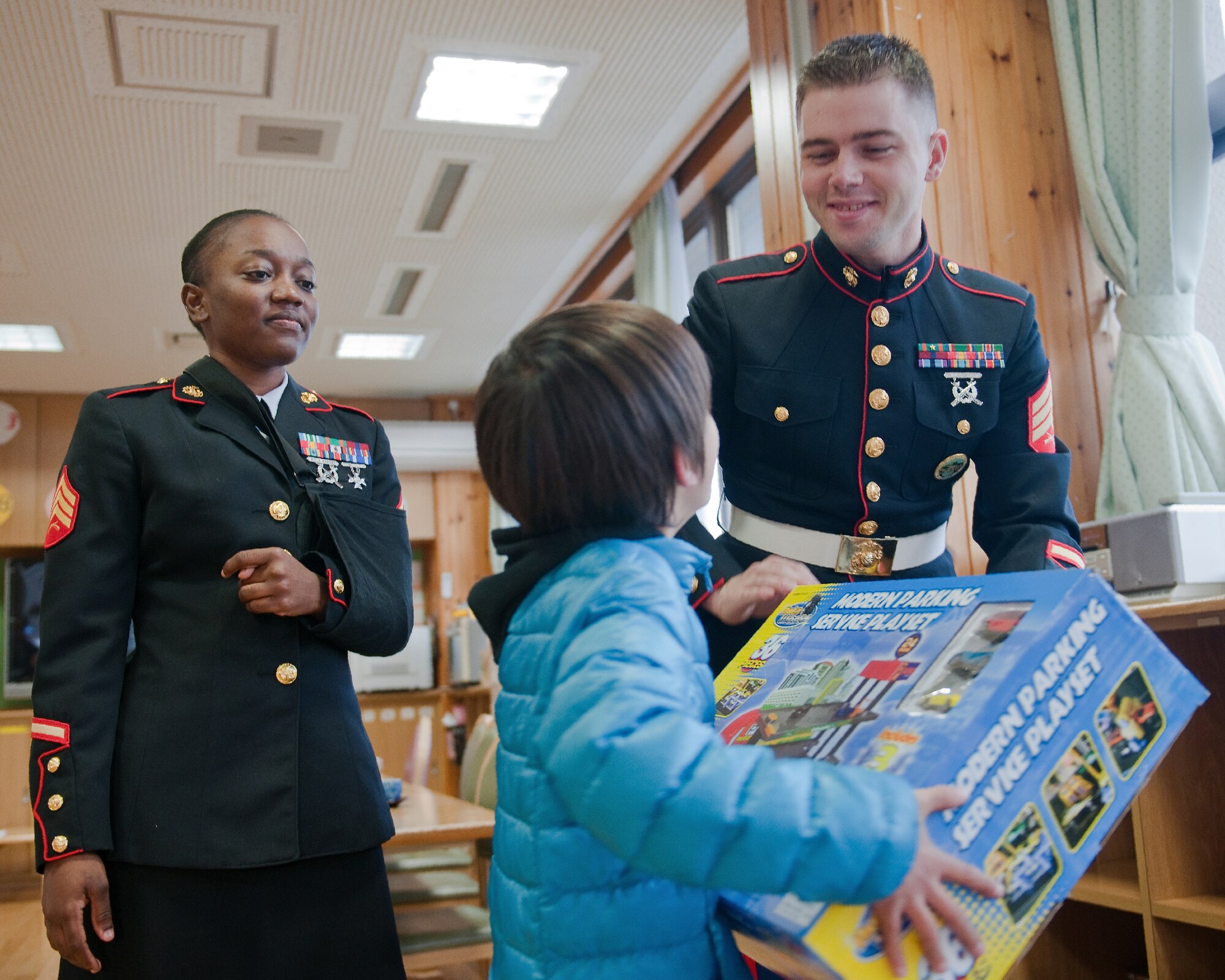 AKIRUNO CITY, Japan -- (right to left) Sgt. Timothy Johnston and Sgt. Stacian Manglay, both from U.S.  Forces Japan, present a child from the Ajiro Orphanage, Akiruno City, Tokyo, Japan, Dec. 16, 2011, with a present donated for the 2011 Toys for Tots drive. Toys for Tots is a U.S. Marine Corps Reserve program that is designed for the collection of new, unwrapped toys during October, November and December each year, for distribution of those toys as gifts to needy children in the community during the holiday season. Marines at Yokota AB distributed the toys collected to children at local orphanages. (U.S. Air Force photo/Osakabe Yasuo)   