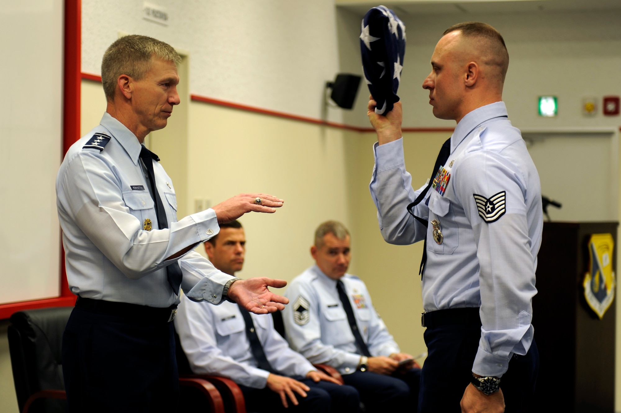 A U.S. Air Force member from the flag detail presents the American flag to U.S. Air Force Lt. Gen. Jeff Remington, 7th Air Force commander and former Kadena Shogun, during the rededication of the Erwin Professional Military Education Center on Kadena Air Base, Japan, Dec. 16, 2011. Remington, a brigadier general at the time, initiated the construction project planning while stationed on Kadena from 2002-2004. (U.S. Air Force photo by Airman 1st Class Maeson L. Elleman/Released)
