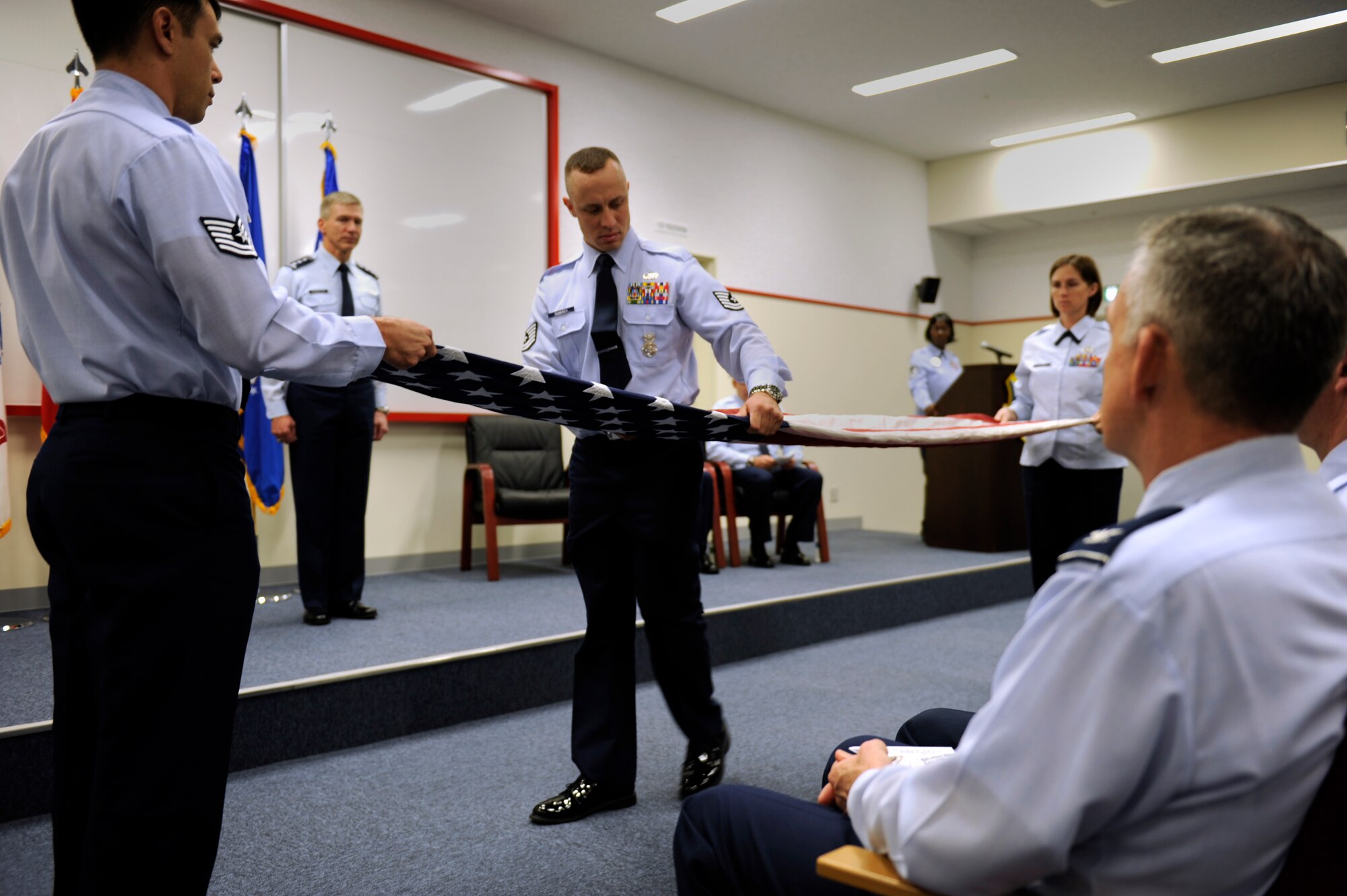 U.S. Air Force Lt. Gen. Jeff Remington, 7th Air Force commander (back left) watches as the flag detail folds the American flag during the rededication of the Erwin Professional Military Education Center on Kadena Air Base, Japan, Dec. 16, 2011. The more than two-year construction project yielded an array of upgrades including a new library and improvements to offices and classrooms to facilitate the further instilment of professional development for NCOs who pass through the halls. (U.S. Air Force photo by Airman 1st Class Maeson L. Elleman/Released)