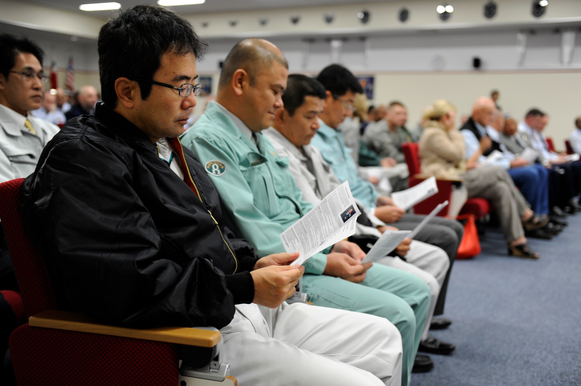 People attending the Erwin Professional Military Education Center rededication read program schedules before the event on Kadena Air Base, Japan, Dec. 16, 2011. The new facility was rededicated following the completion of the more than two-year construction project. (U.S. Air Force photo by Airman 1st Class Maeson L. Elleman/Released)