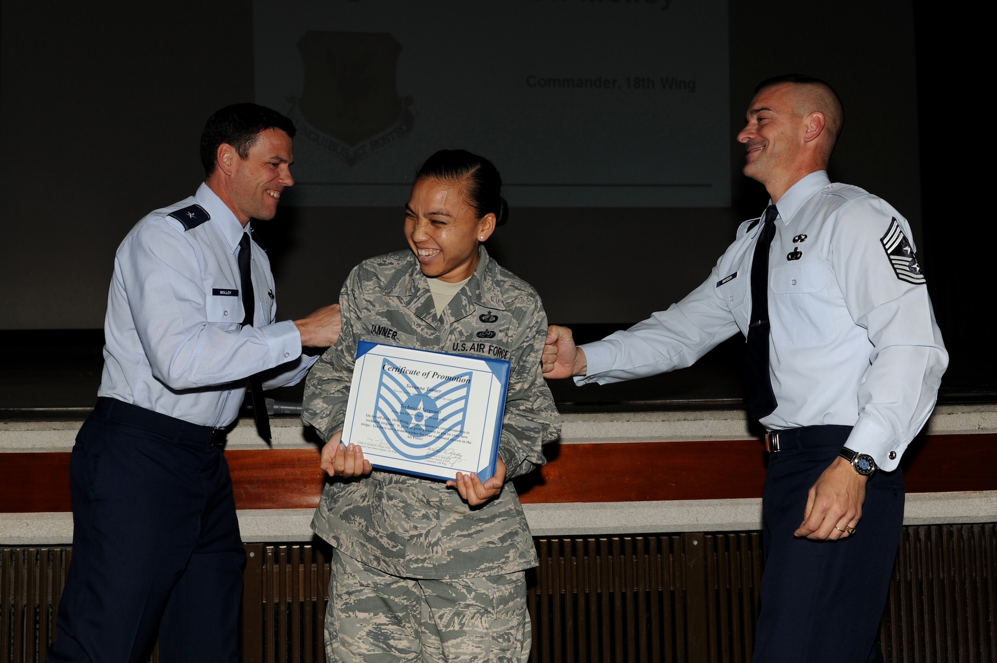 Staff Sgt. Sovanna Tanner, 18th Contracting Squadron specialist, receives a Stripes for Exceptional Performers promotion from Brig. Gen. Matt Molloy, 18th Wing commander, and Chief Master Sgt. Mark Marson, 18th Wing command chief, at a holiday safety briefing, Dec. 19, 2011 on Kadena Air Base, Japan. Tanner and Staff Sgt. Steven Javinar 18th Civil Engineer Squadron water fuel systems maintainer were immediately promoted to technical sergeant for their exceptional performance and achievements. (U.S. Air Force photo by Junko Kinjo/Released)