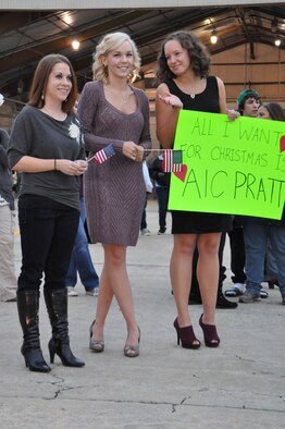 Kieran Adams (left), girlfriend of Airman 1st Class William Foxx, Heather Smith, wife of Airman 1st Class Paul Smith, and Rachel Pratt (right), spouse of Airman 1st Class Robert Pratt, hold signs and wave flags as they wait for their significant others to return home from a deployment on Seymour Johnson Air Force Base, N.C., Dec. 20, 2011. Along with more than 100 Airmen, 12 F-15E Strike Eagles will return over the next few days from Bagram Airfield, Afghanistan. (U.S. Air Force photo by Airman 1st Class Mariah Tolbert)