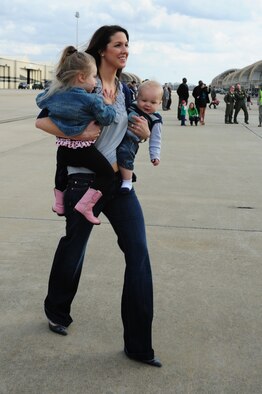 Jessica Higgins carries daughter Sagen, 2 years old, and Cannon, 7 months old, across the flightline to greet their father, Capt. Josh Higgins, 335th Fighter Squadron F-15E Strike Eagle pilot, after his return to Seymour Johnson Air Force Base, N.C., Dec. 20, 2011. Aircrew members from the 335th Fighter Squadron and more than 80 support Airmen are scheduled to return in the coming days from a deployment to Bagram Airfield, Afghanistan. The Higgins' hail from Carthage, Texas. (U.S. Air Force photo by Senior Airman Rae Perry)