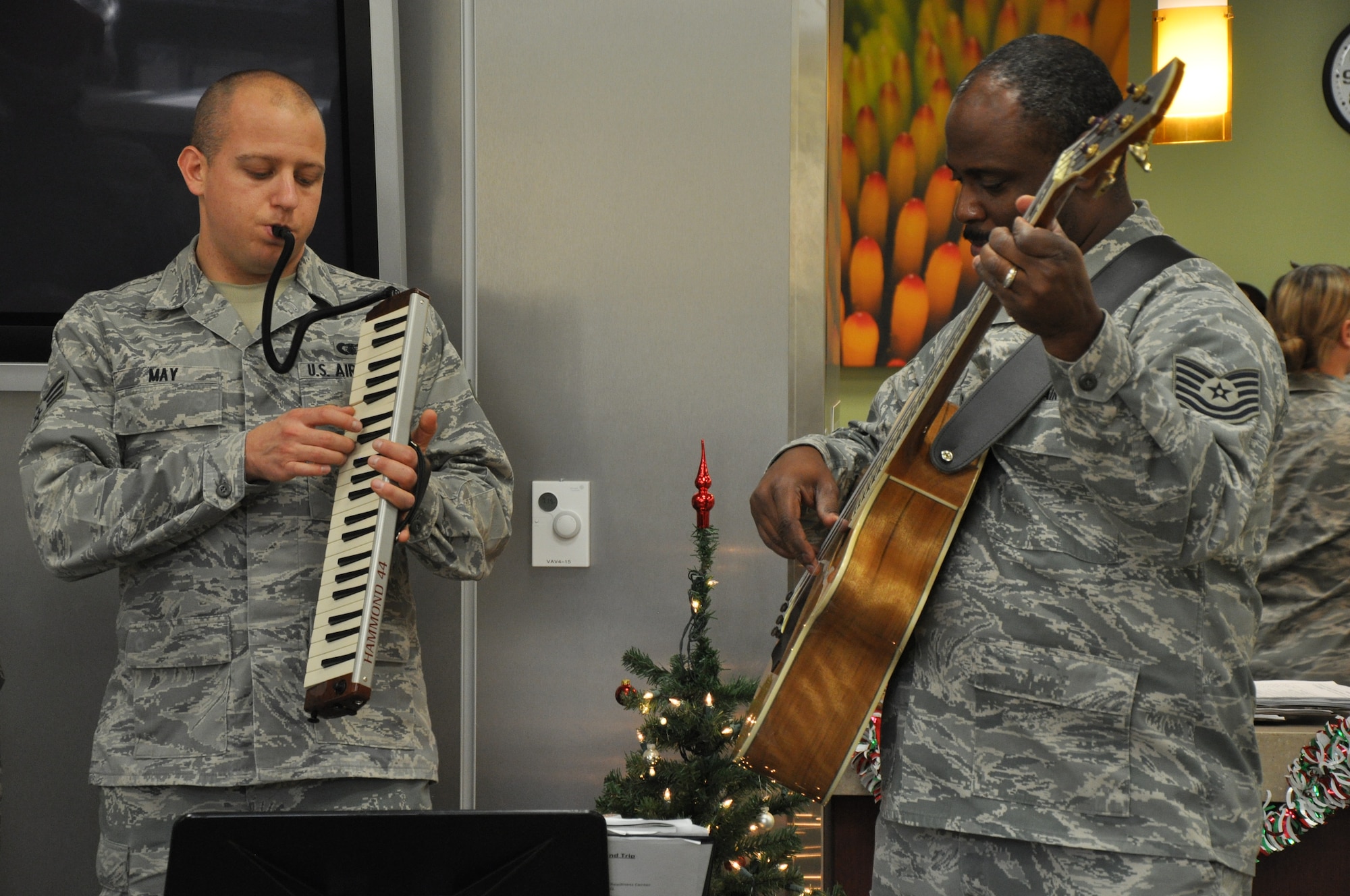 Senior Airman Brandon May plays the melodica and Tech. Sgt. Terry J. Grace strums the bass while they perform holiday songs for the medical clinic at Beale Air Force Base Calif., Dec. 14, 2011. Both are members of the rock band Mobility based out of Travis AFB. (U.S. Air Force photo by Staff Sgt. Robert M. Trujillo/Released)