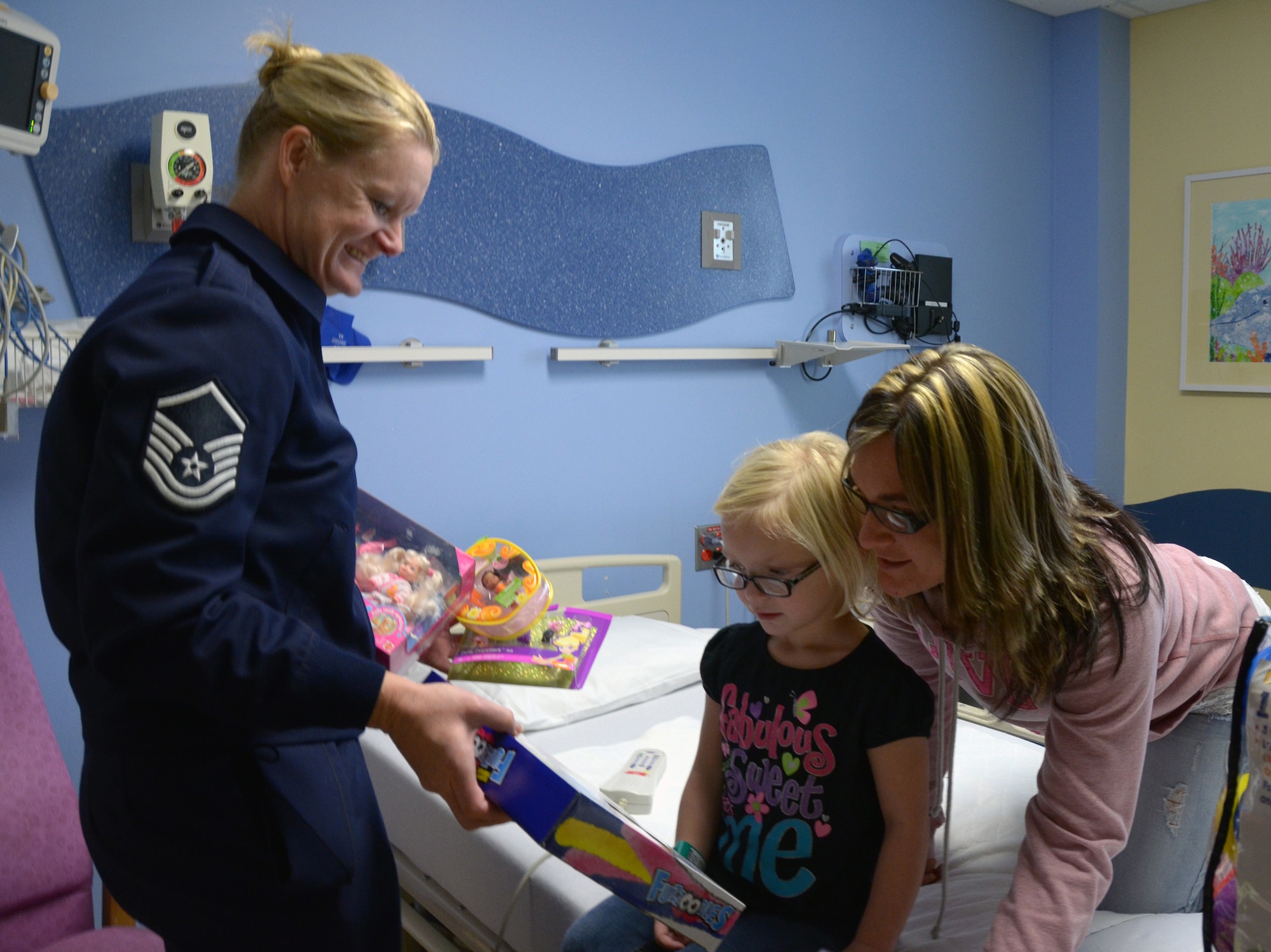 WRIGHT-PATTERSON AIR FORCE BASE, Ohio - Master Sgt. Linda Thrasher, a reservist assigned to the 445th Airlift Wing’s 87th Aerial Port Squadron, presents 4-year-old Hayley Elam a Christmas gift at the Dayton Children’s Hospital Dec. 16. 87APS members have worked with the hospital for more than 22 years to bring a little more happiness to children who are hospitalized there over the holidays. (U.S. Air Force photo/Capt. John Stamm)